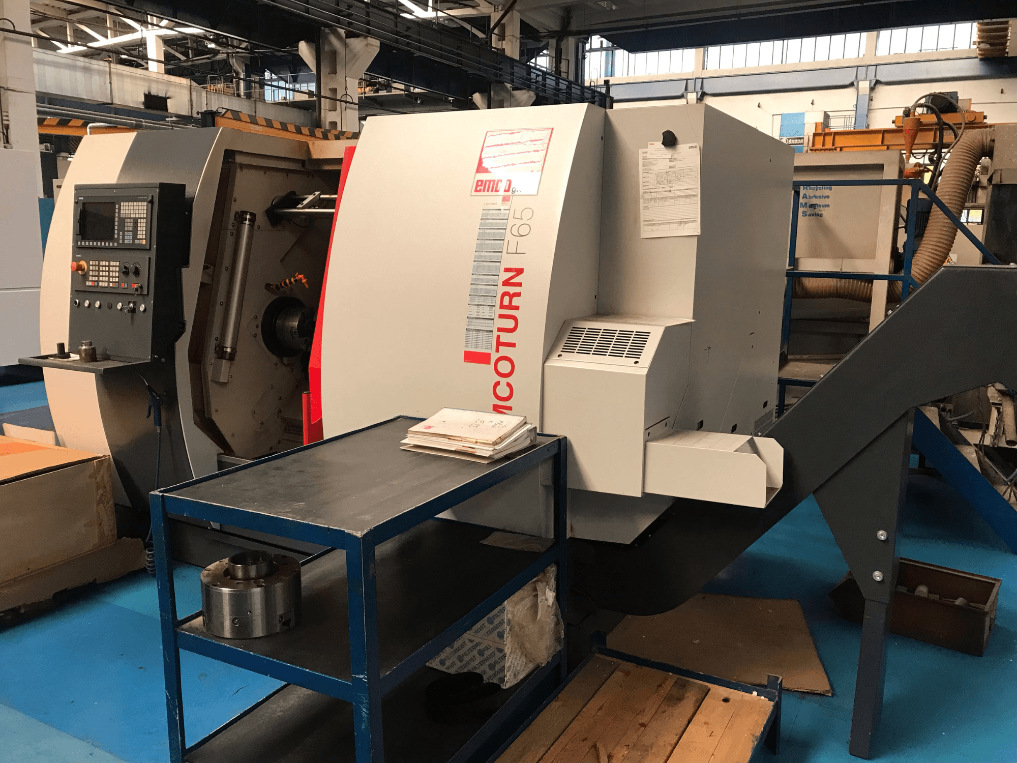 Bočni pogled na horizontalni tokarski stroj EMCO Emcoturn 65, s prikazom kontrola i radnog prostora s metalnim dijelovima u blizini.