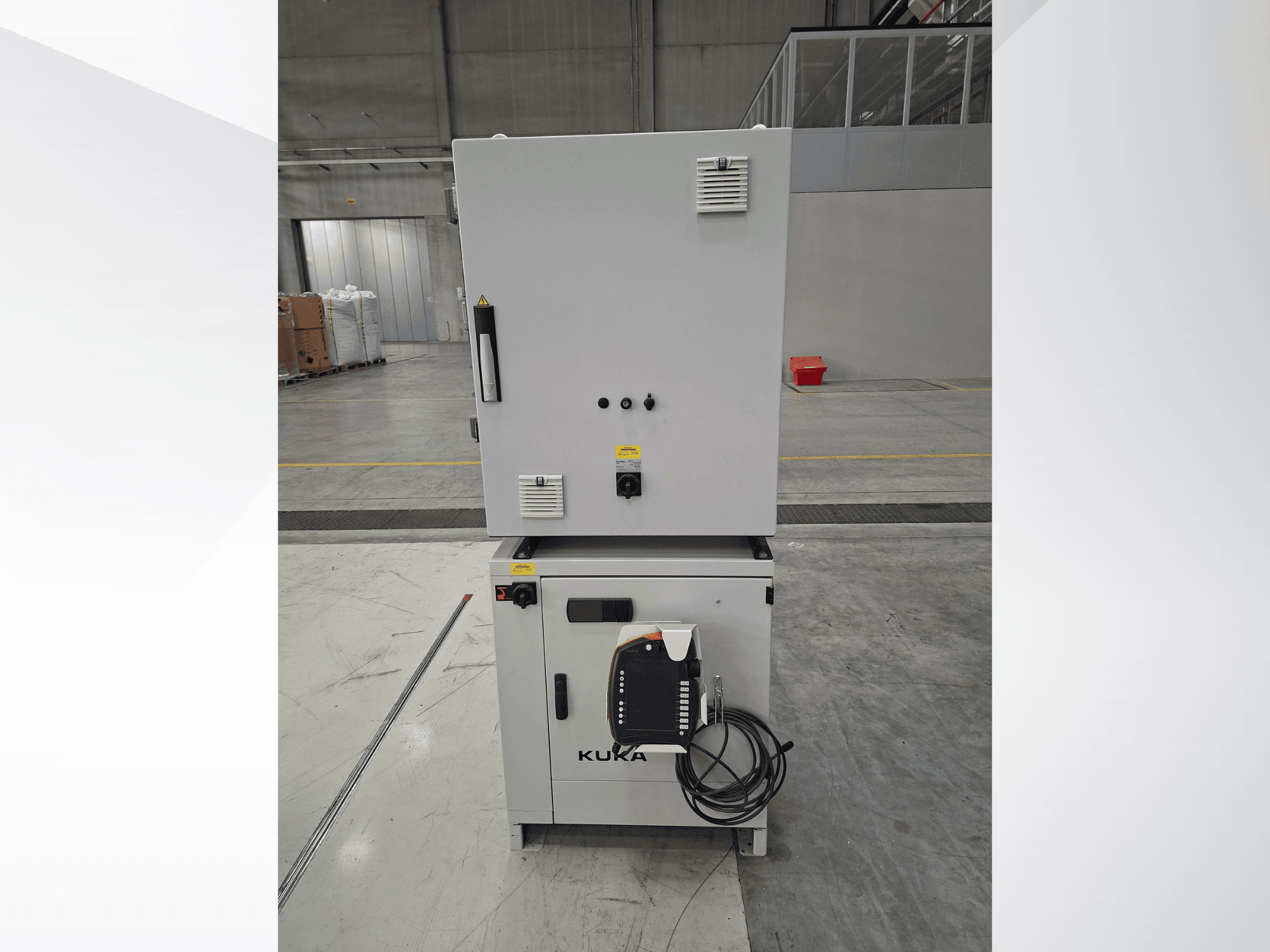 KUKA KR 90 R2700 PRO C4 FLR kontroler robotske ruke, prednji pogled s upravljačkom pločom i sigurnosnim naljepnicama u prostranom skladištu.