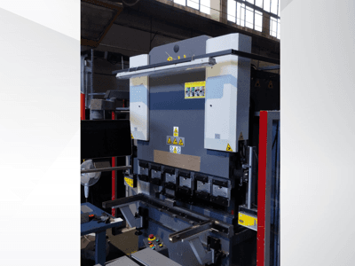 Stroj za savijanje preše, prednji pogled. Ima vidljive kontrole, sigurnosne naljepnice i više držača matrica za precizno savijanje.