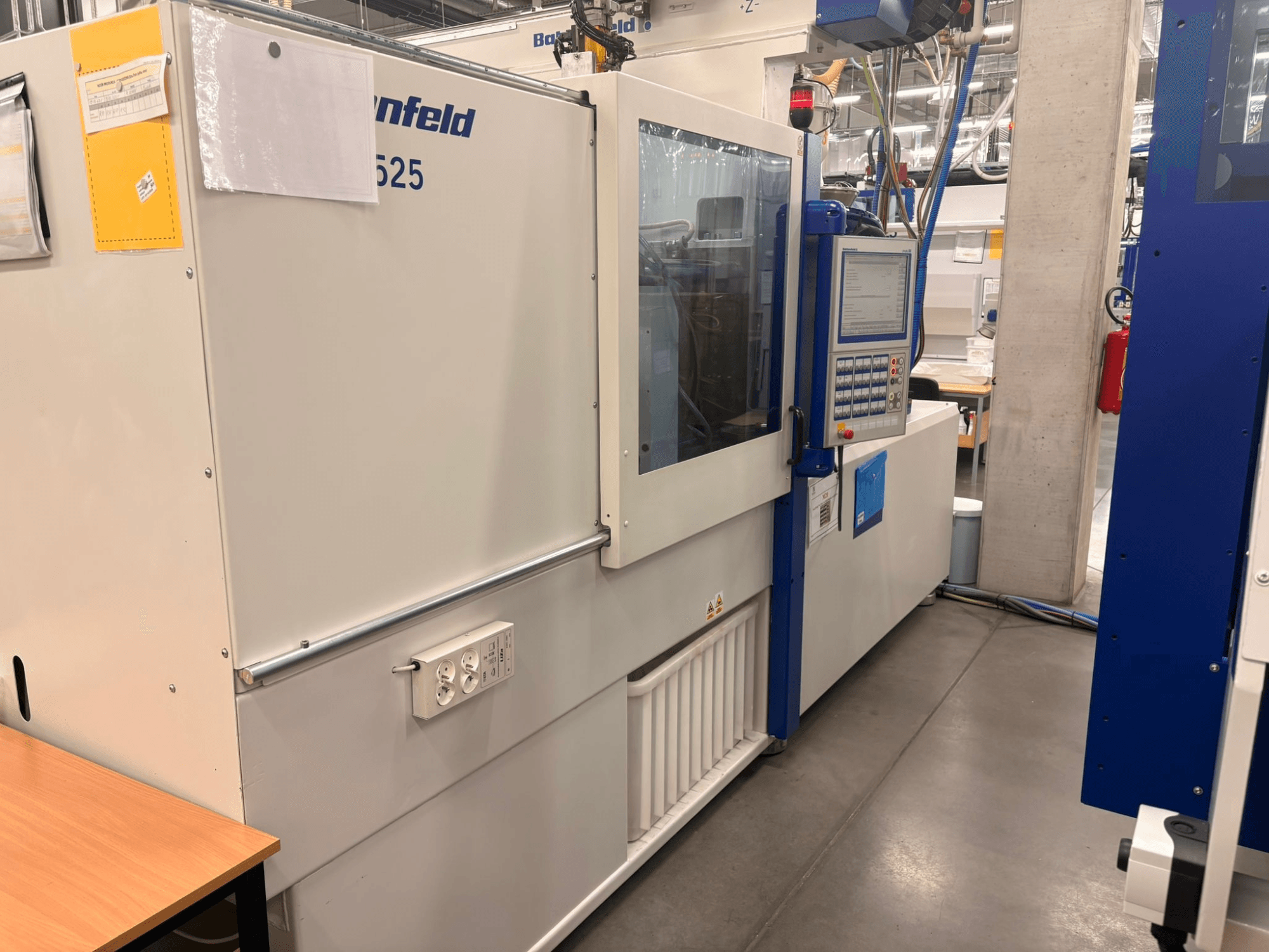 Strojevi tvrtke Arburg, model 620S, prednji pogled s upravljačkom pločom i priključcima za napajanje u tvorničkom okruženju.