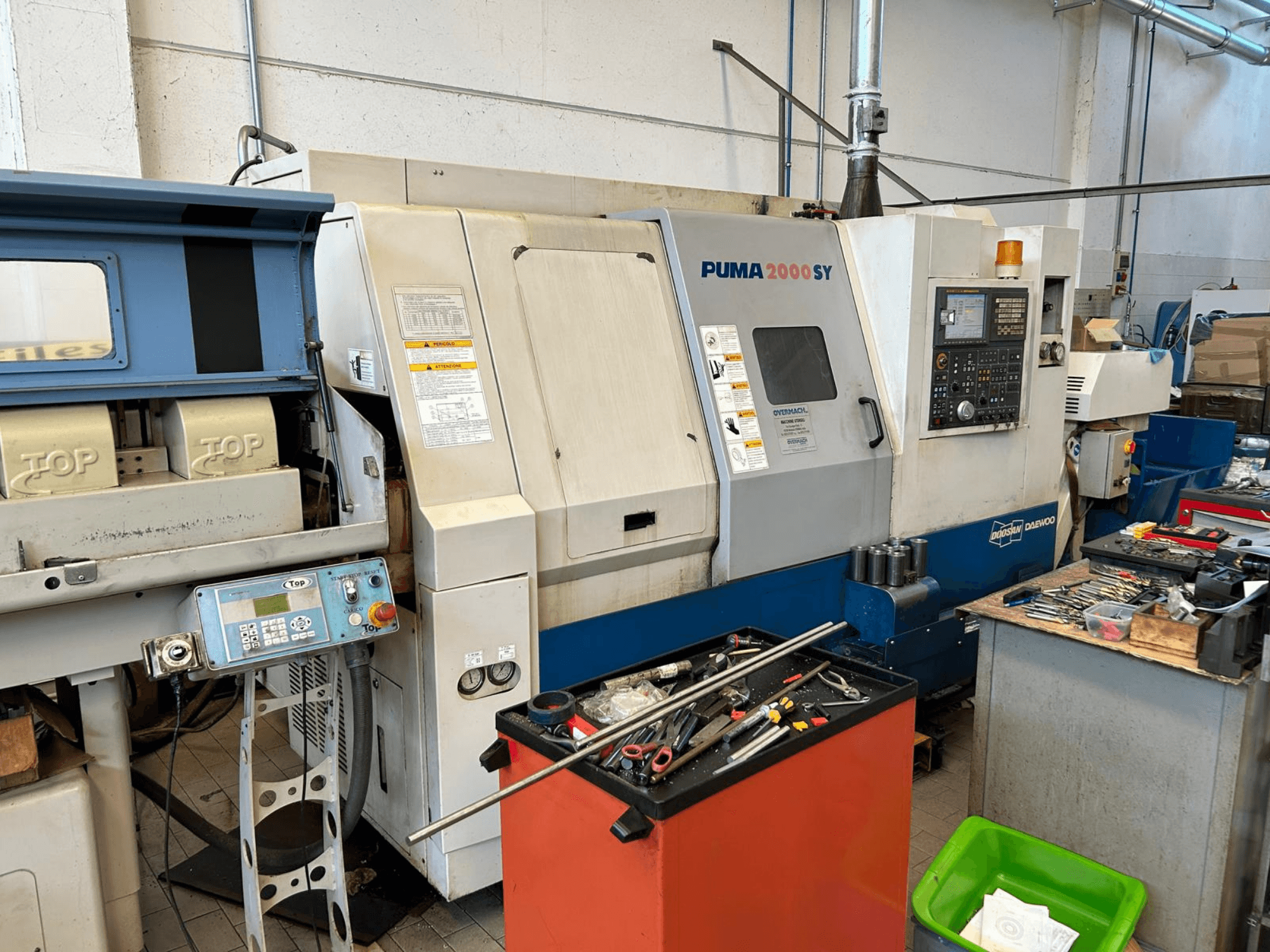 Horizontalni tokarski stroj DOOSAN PUMA 2000SY u radionici, bočni pogled s upravljačkom pločom i alatima u blizini.