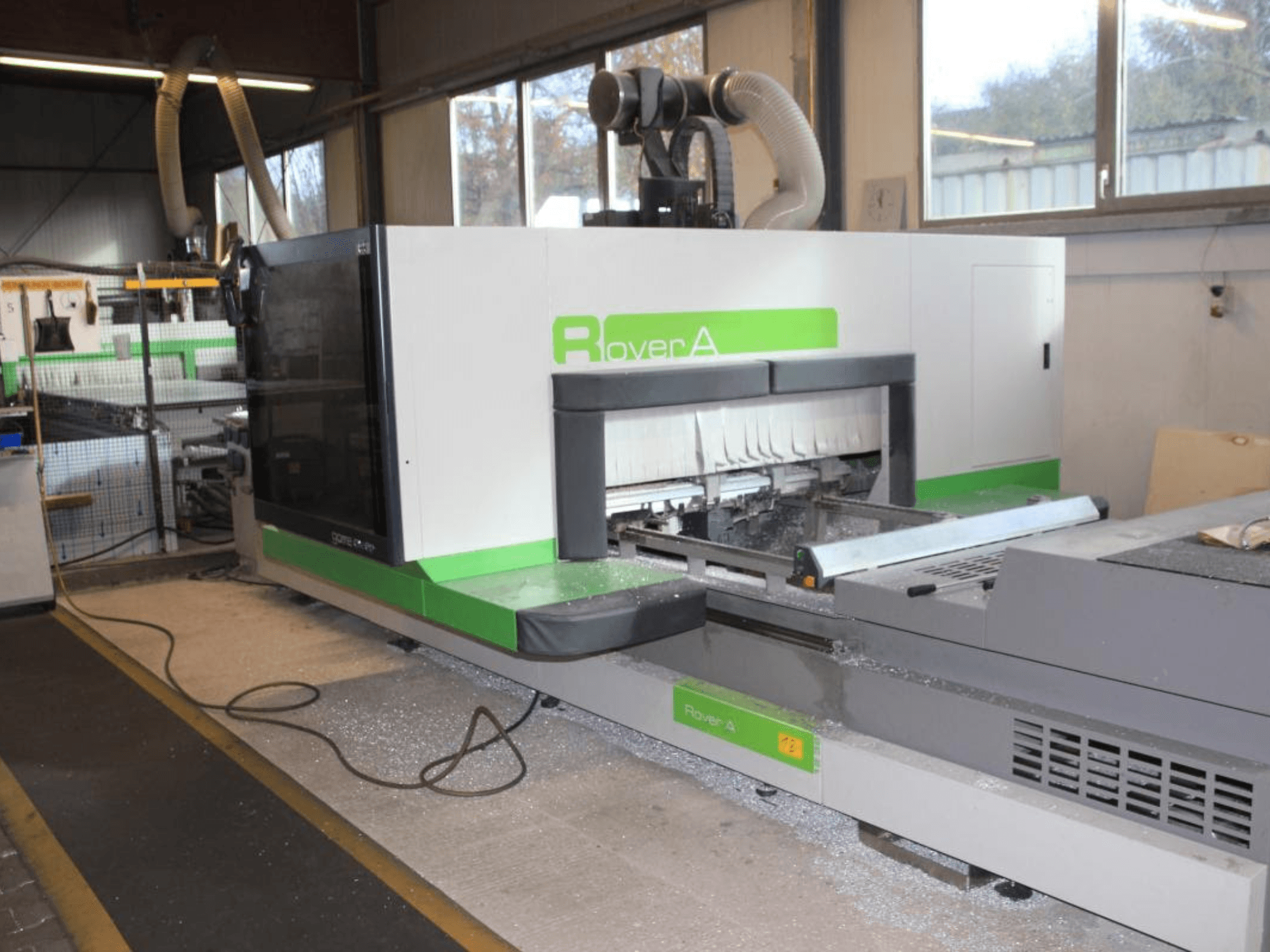 BIESSE Rover A 1232 CNC glodalica, bočni pogled koji prikazuje područje rezanja i upravljačku ploču u industrijskom okruženju.