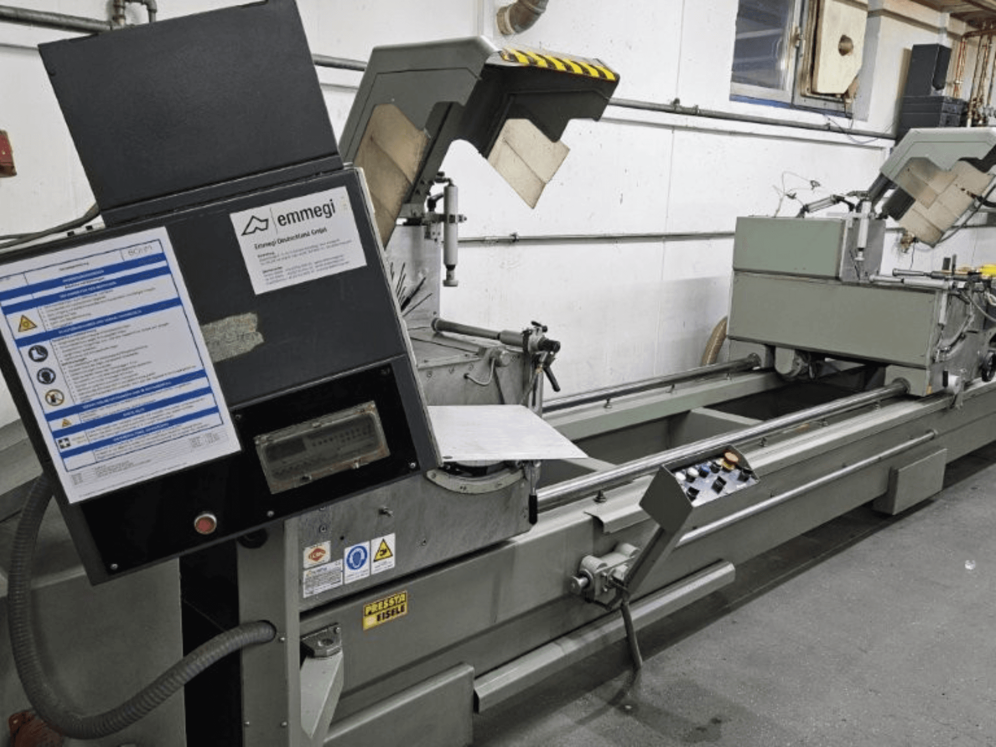 Industrijski stroj za rezanje Emmegi, prednji pogled, sadrži upravljačku ploču, sigurnosne naljepnice i operativne komponente.