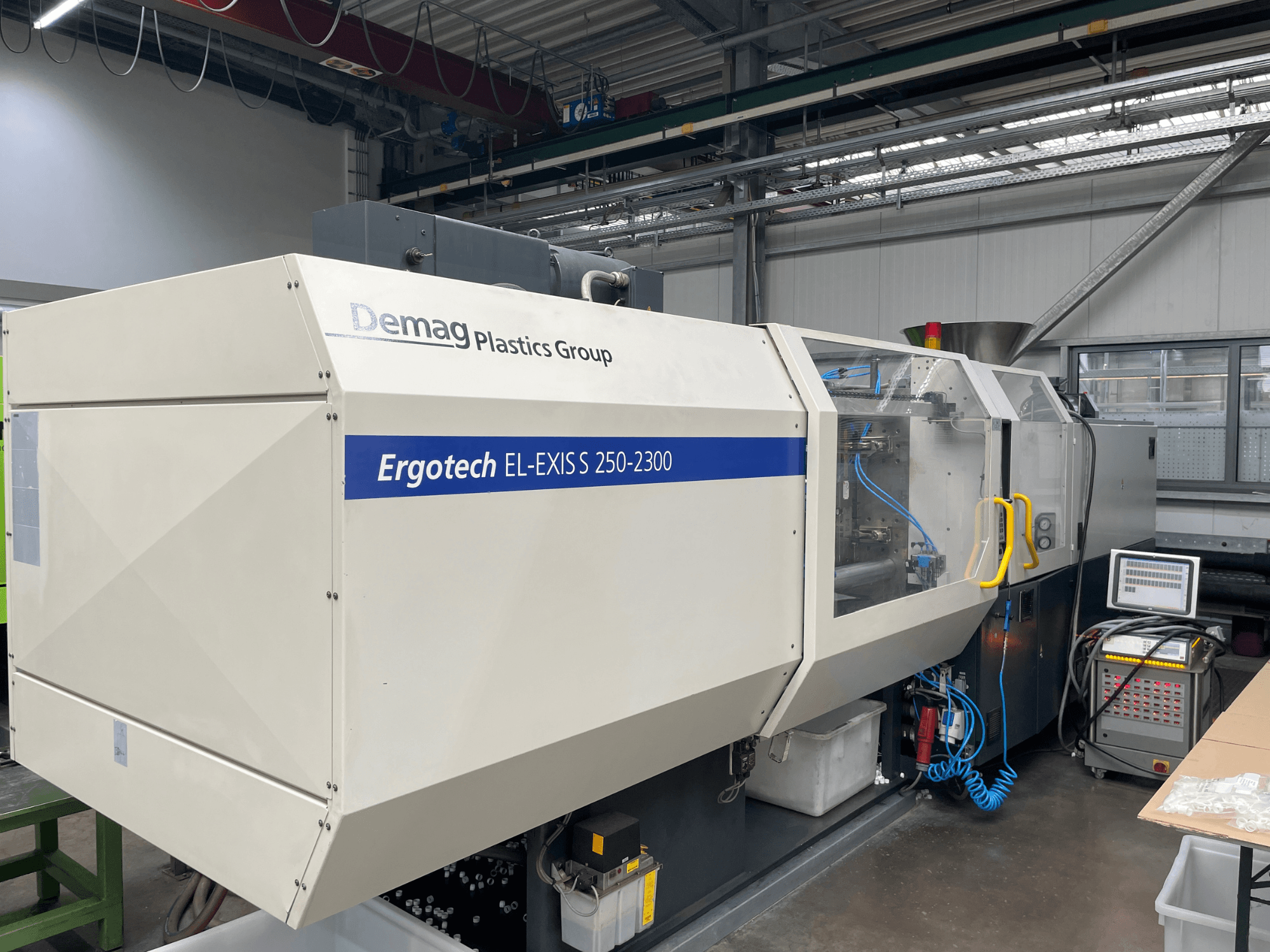 Stroj za brizganje plastike Demag Ergotech EL-EXIS S 250-2300, bočni pogled, s prikazom upravljačke ploče i sustava za dovod.