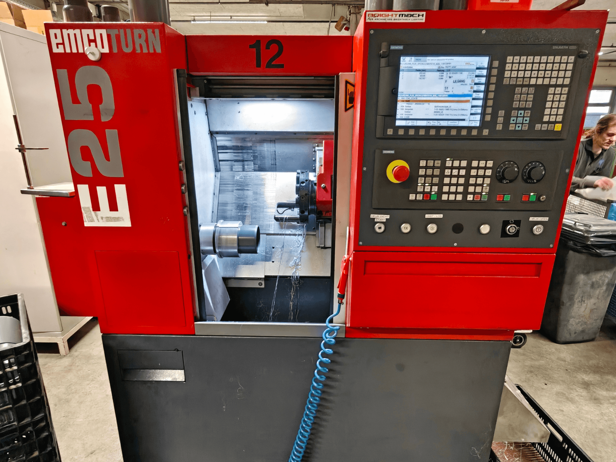 Prednji pogled na stroj EMCO TURN E25, s upravljačkom pločom, držačem alata i unutarnjim prostorom s vidljivim alatom za rezanje.