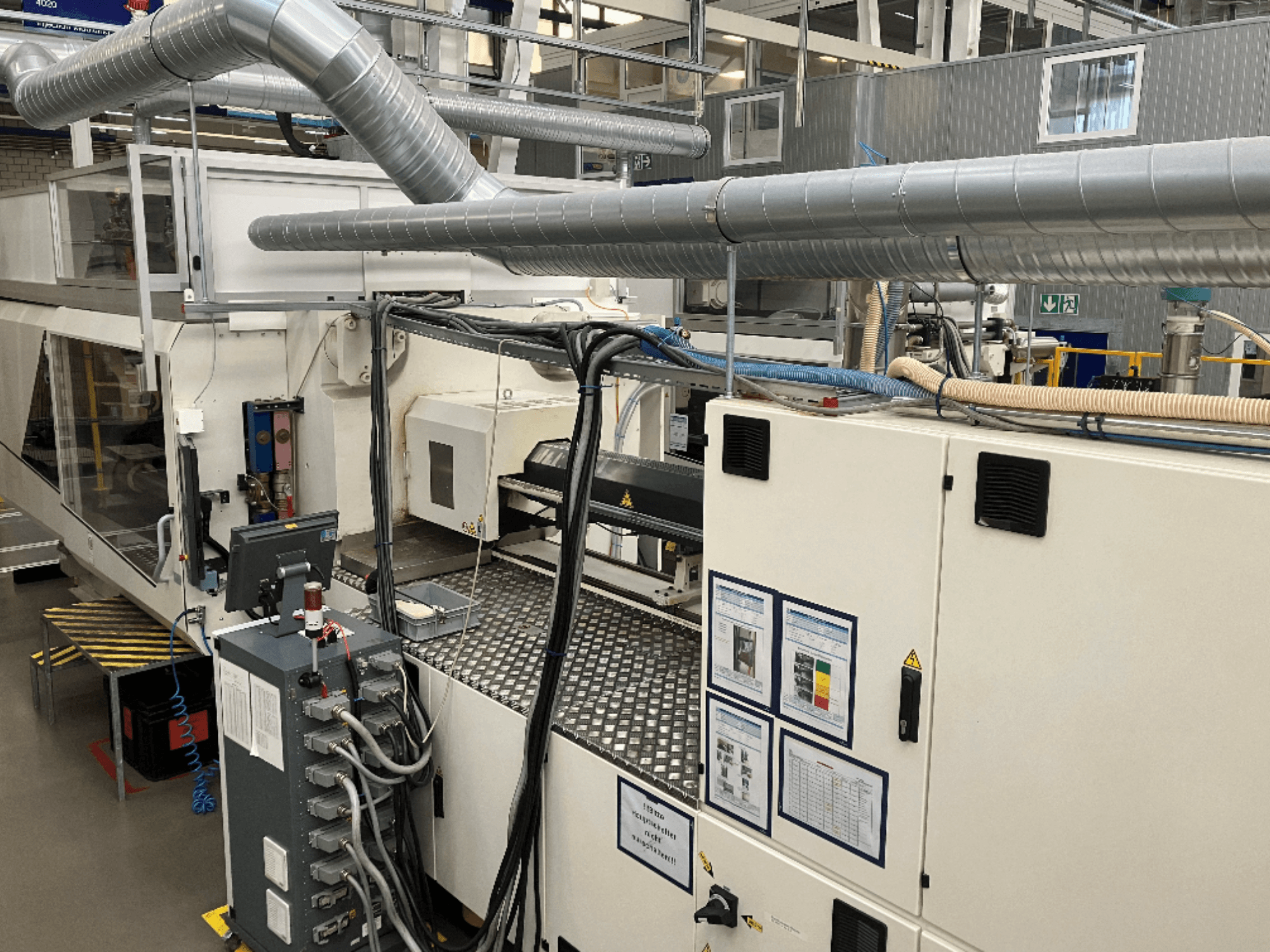 Industrijski strojevi s opsežnim cjevovodima, upravljačkom pločom i priručnicima za uporabu, gledani iz perspektive odozgo prema dolje.