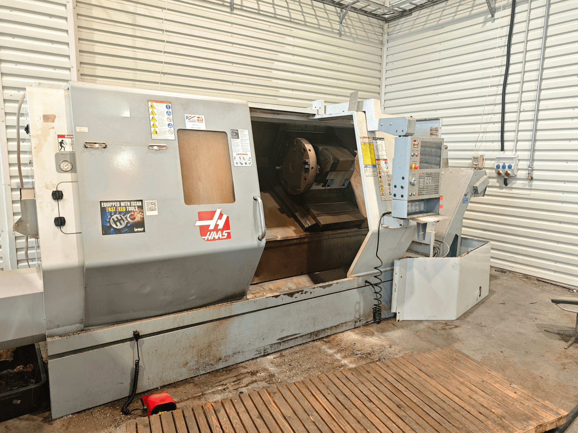 Haas SL-40HE horizontalni tokarski stroj, prednji pogled, prikaz upravljačke ploče, radnog prostora i sigurnosnih naljepnica.