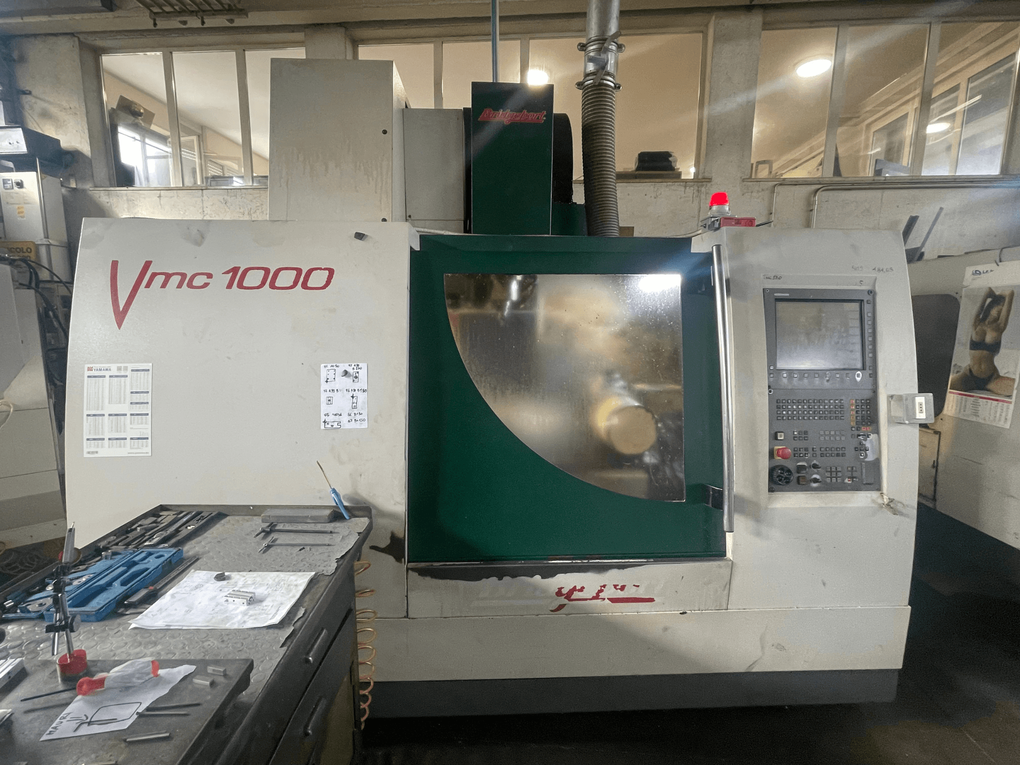 Vertikalni obradni centar Bridgeport VMC 1000/30, prednji pogled, s prikazom upravljačke ploče i glavnog tijela, s alatima u blizini.