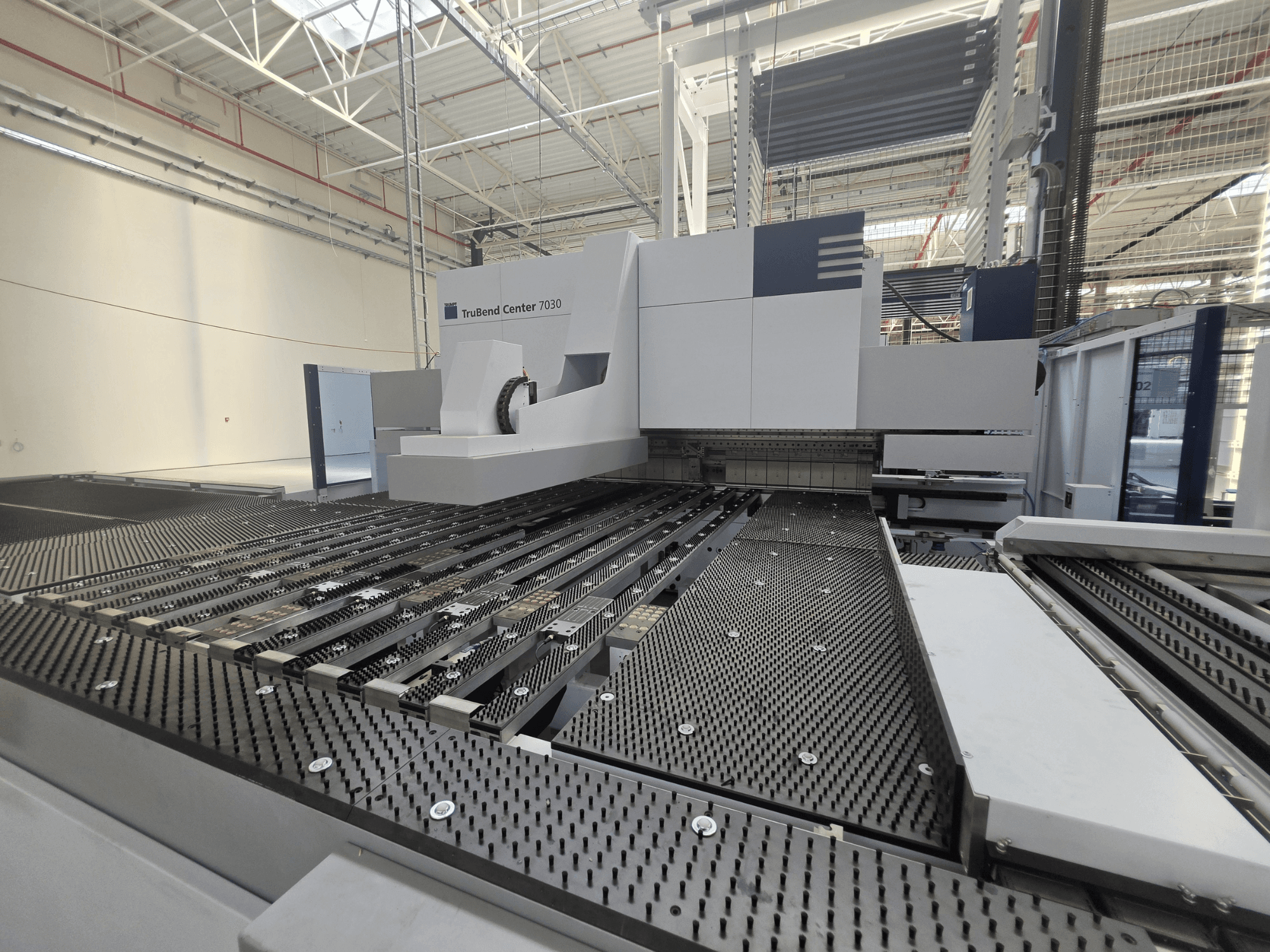 TRUMPF TruBend Center 7030 stroj za savijanje u tvorničkom okruženju, prednji pogled koji prikazuje zamršeni radni stol i ruku za savijanje.