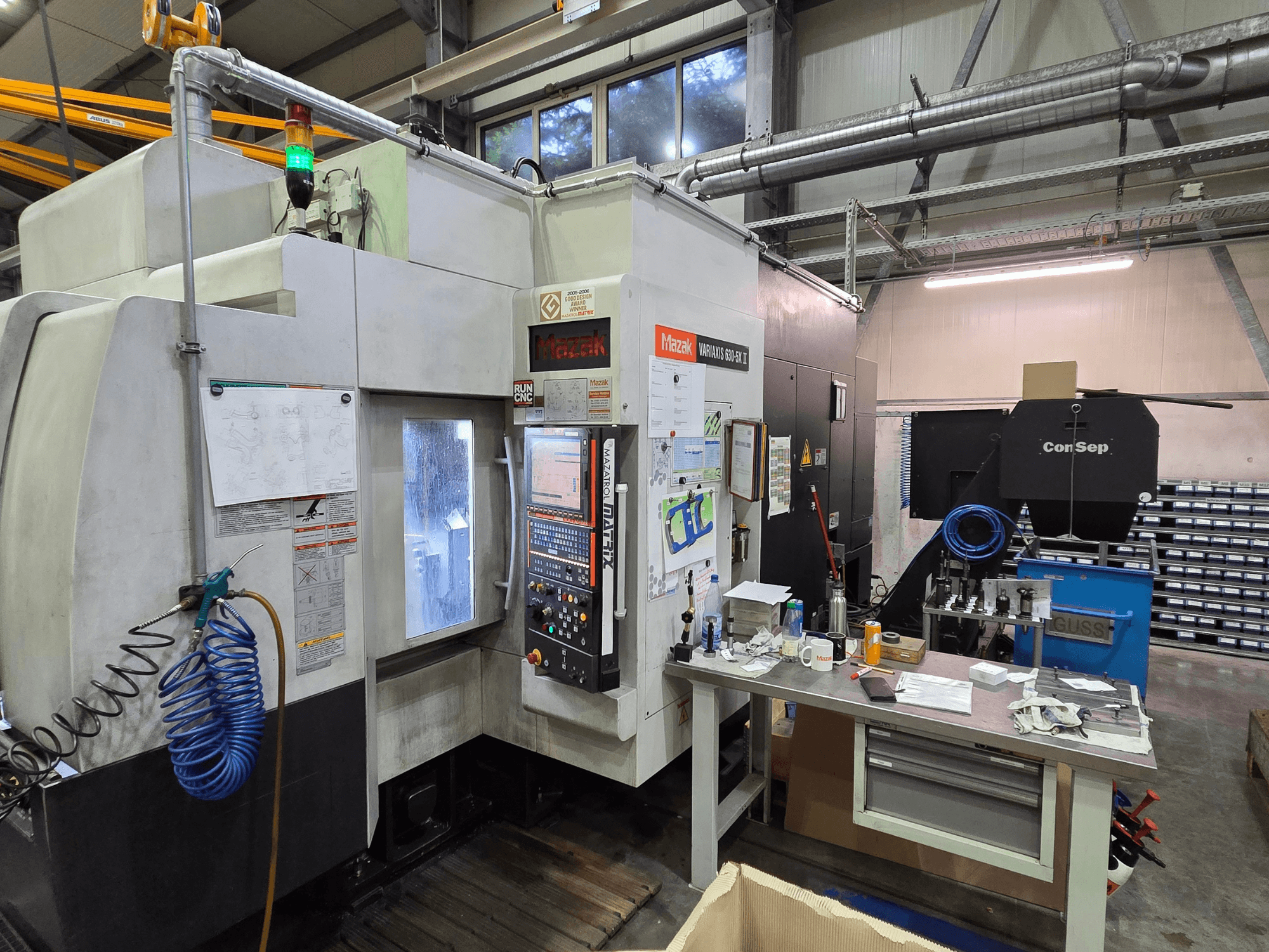 Mazak Variaxis 630-5X CNC stroj u radionici, prednji pogled s upravljačkom pločom, crijevom i priborom na bočnom stolu.