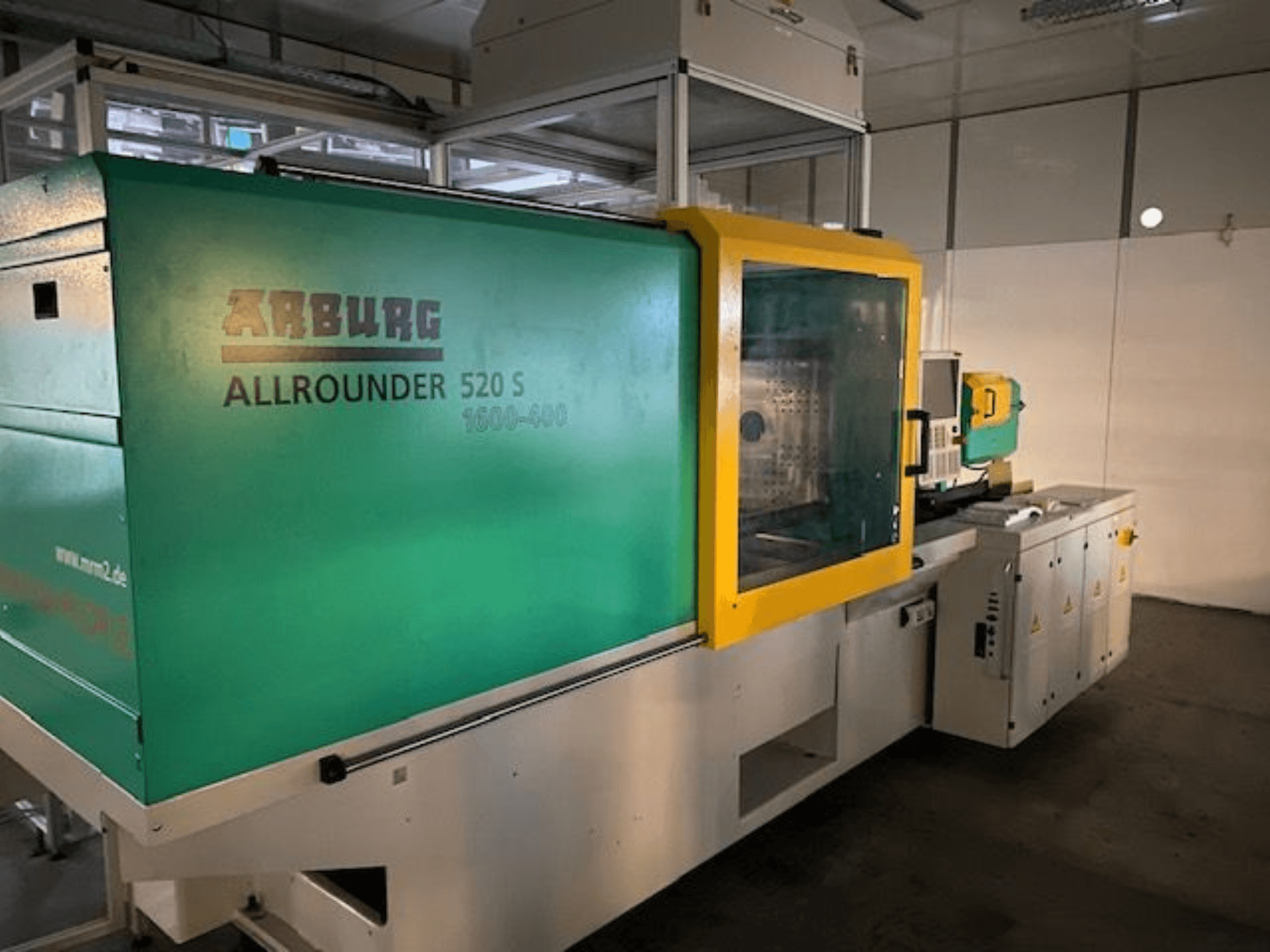 Stroj za brizganje plastike Arburg Allrounder 520 S, bočni pogled, zeleno-žuta vanjština, vidljivi tehnički detalji.