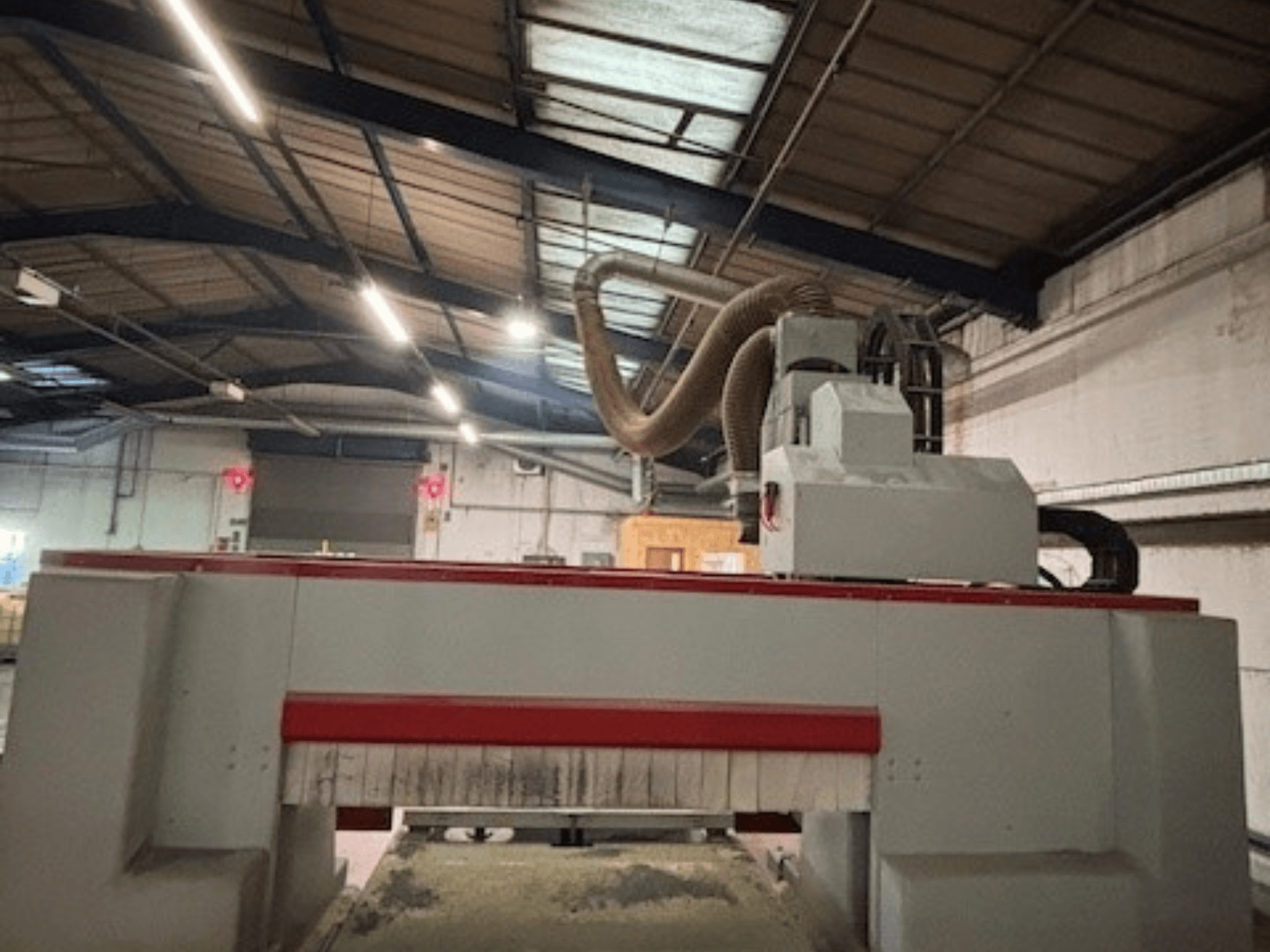 CNC glodalica u radionici, bočni pogled s istaknutim crvenim i sivim dizajnom, priključen sustav za usisavanje prašine.