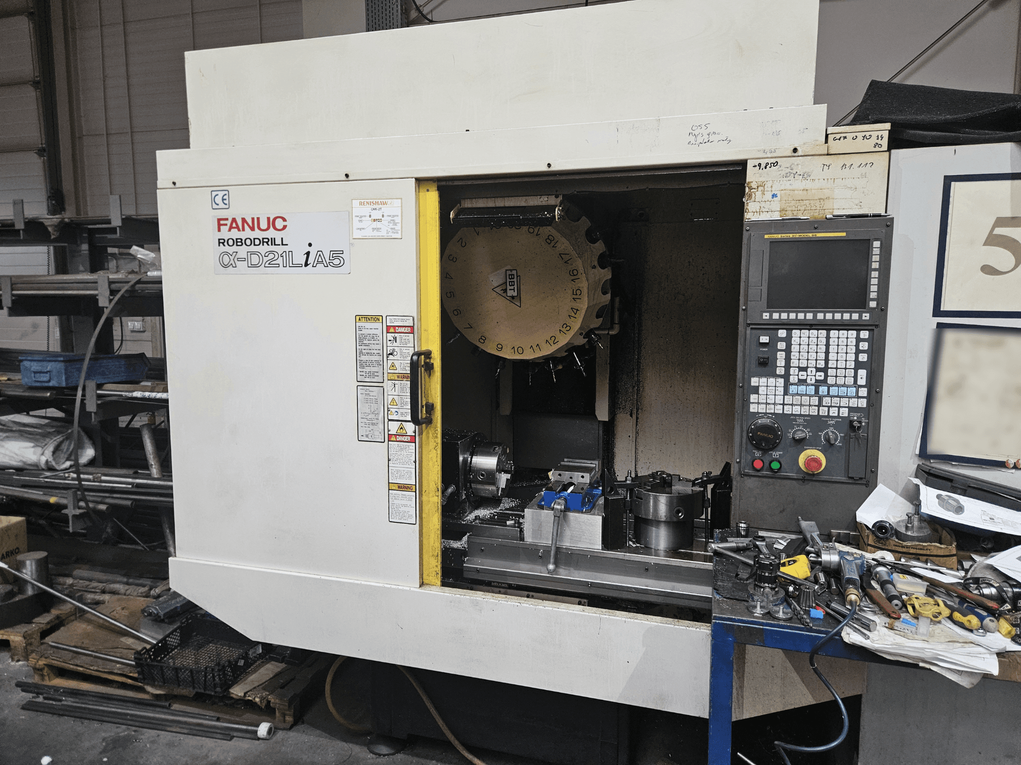 FANUC Robodrill α-D21LiA5, prednji pogled s držačem alata i upravljačkom pločom, okružen alatima i opremom u radionici.