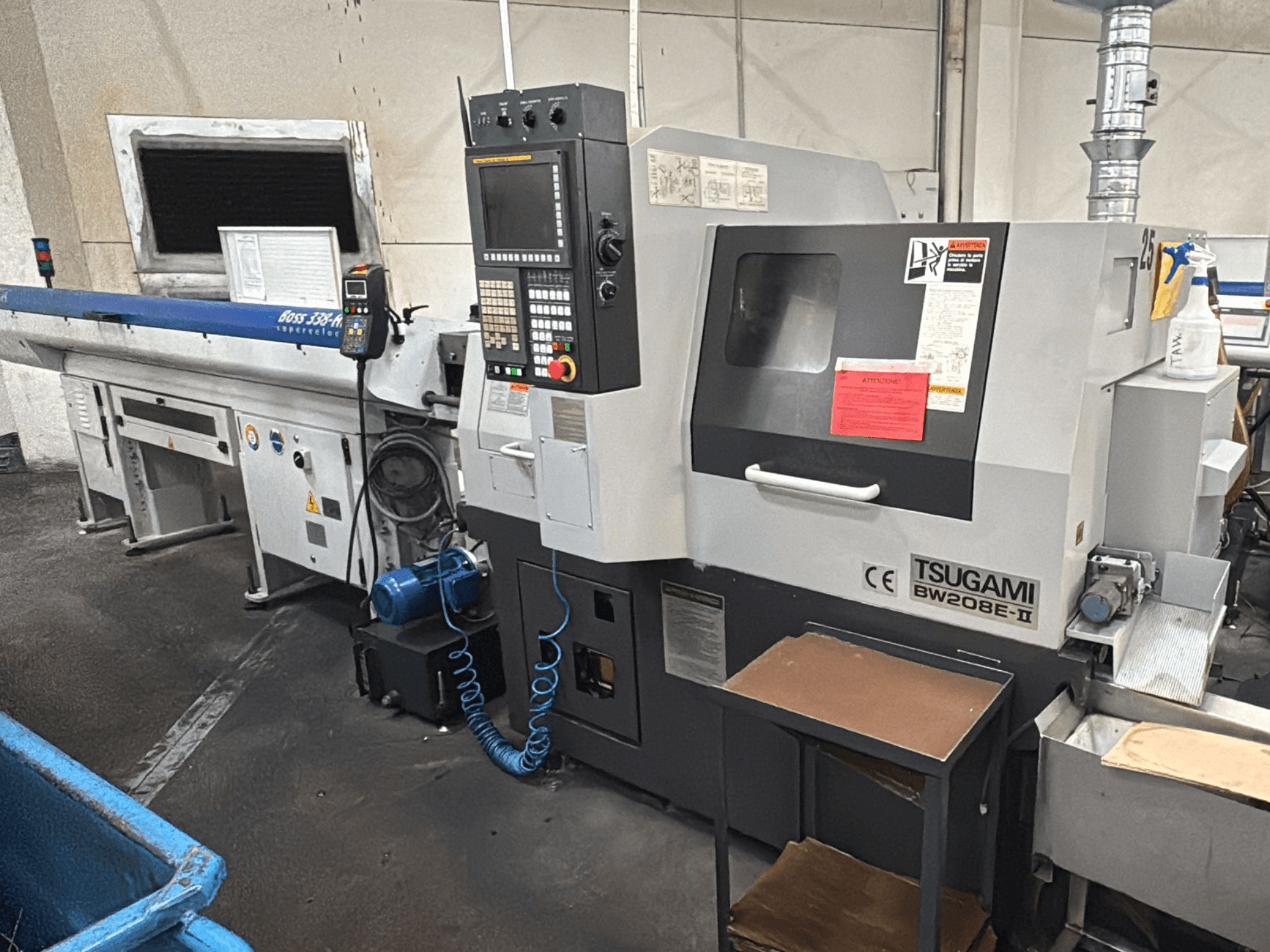 CNC stroj Tsugami BW208E-II u radionici, prikazan iz prednjeg kuta, s vidljivom upravljačkom pločom i sigurnosnim naljepnicama.