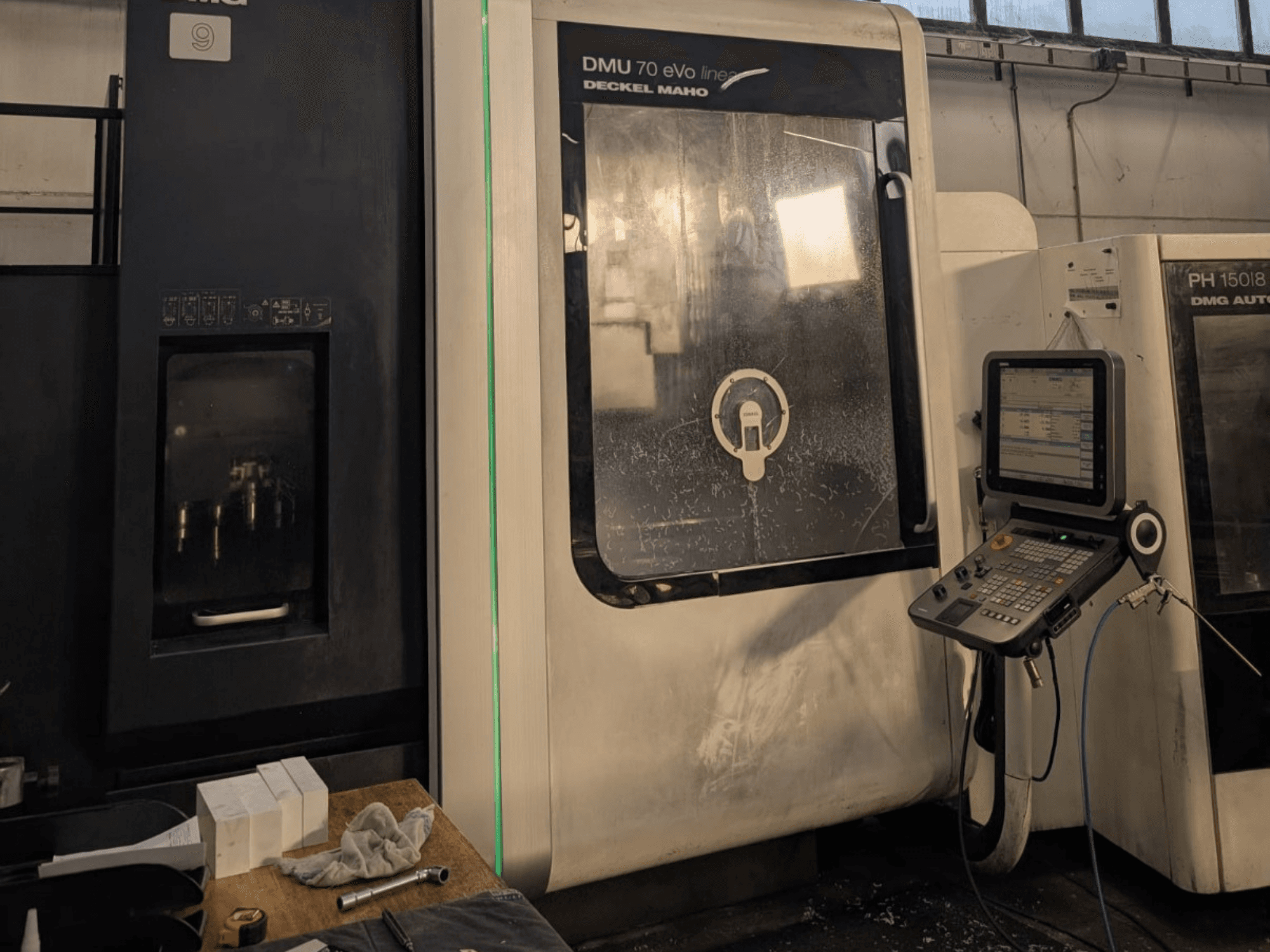 DMG DECKEL MAHO DMU 70 EVO Linearni vertikalni obradni centar, prednji pogled s vidljivom upravljačkom pločom, alatima i radnim prostorom.