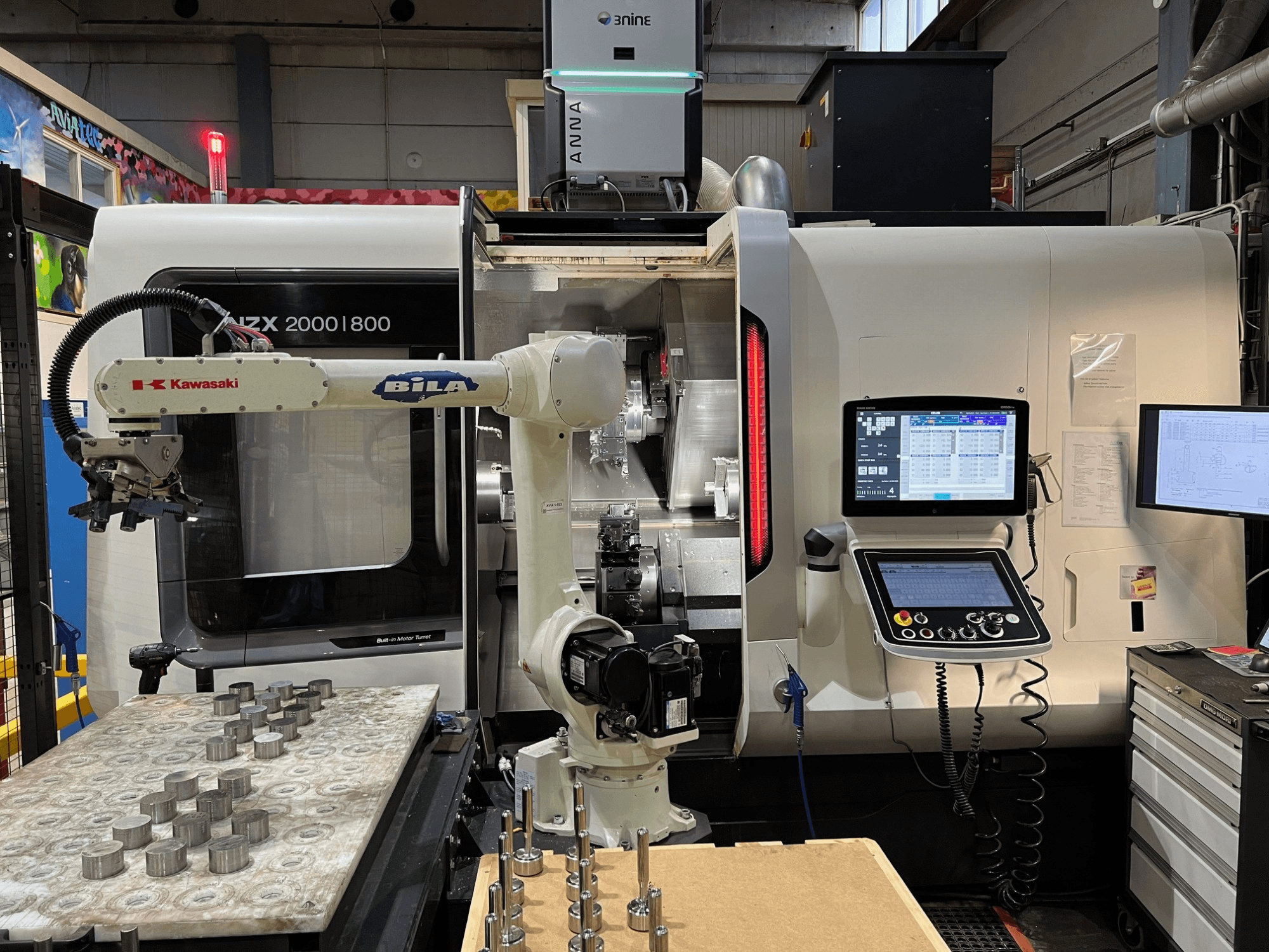 Horizontalni tokarski stroj DMG MORI NZX 2000/800SY u radionici, s vidljivom robotskom rukom i upravljačkim elementima Kawasaki.