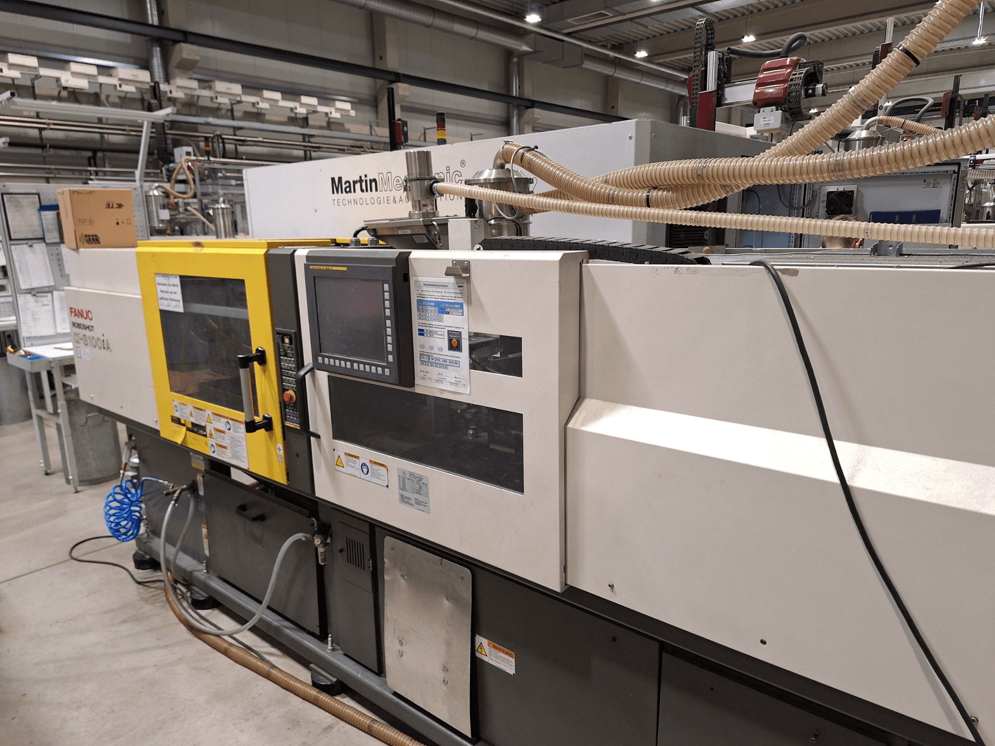 FANUC Roboshot S100iA električni stroj za brizganje plastike, bočni pogled, opremljen zaslonom osjetljivim na dodir i sigurnosnim naljepnicama.