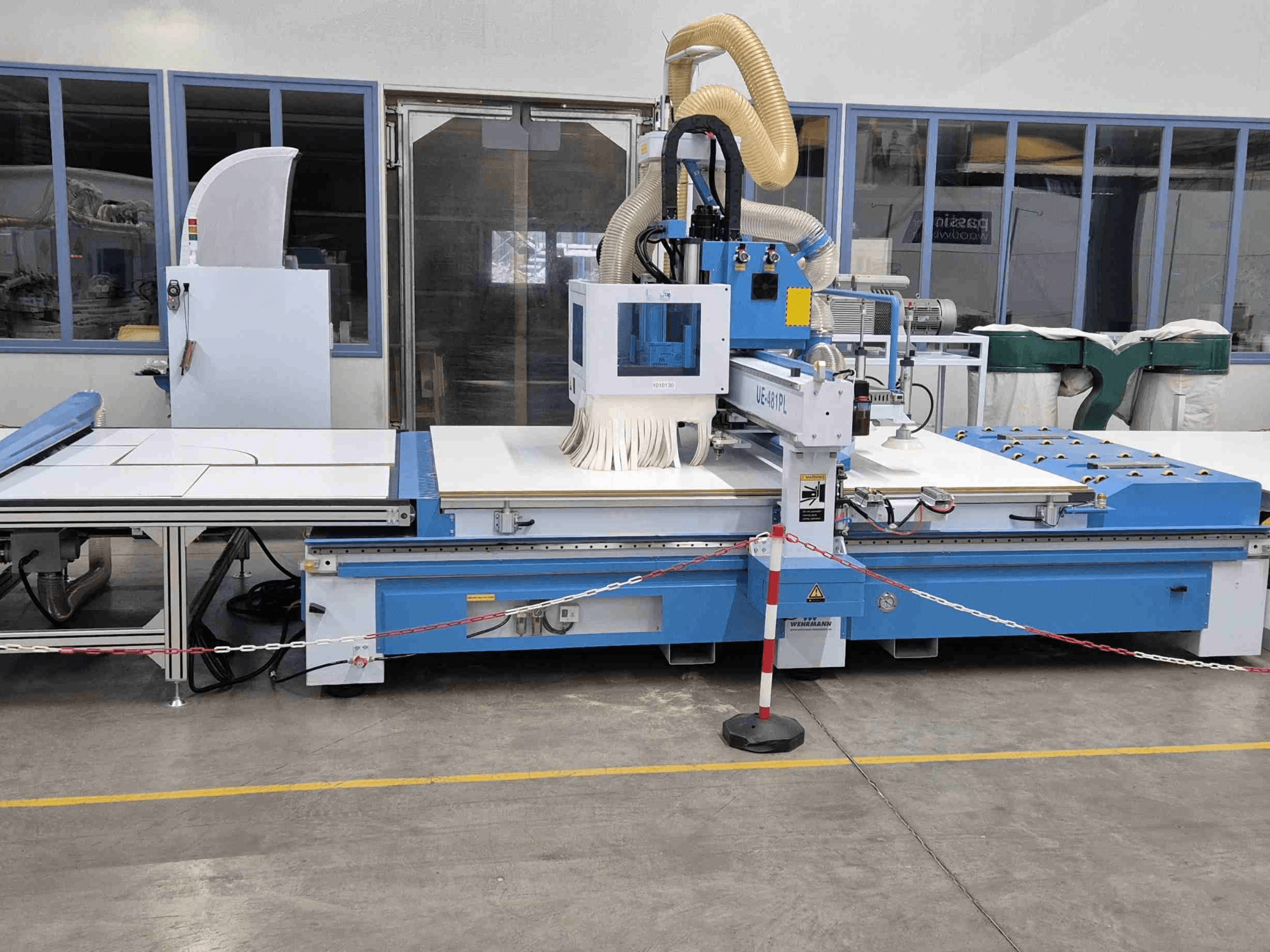 Plavi CNC glodalica UE-621PL s prednje strane, s velikim stolom za rezanje i priključenim sustavom za usisavanje prašine.