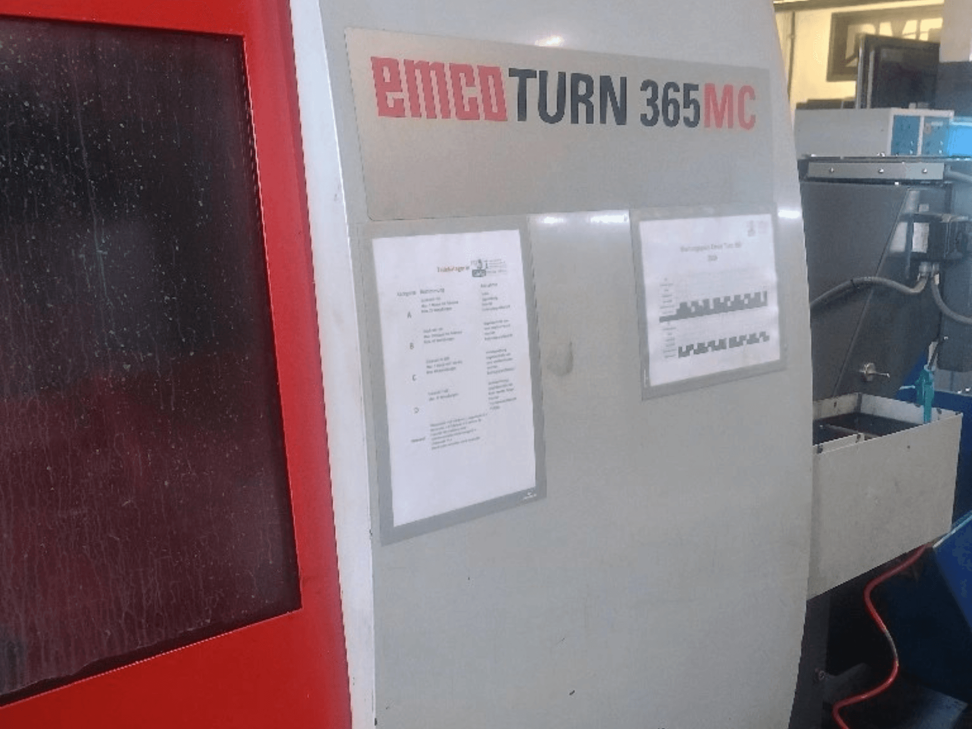 EMCO EmcoTurn 365 MC horizontalni tokarski stroj, bočni pogled s vidljivom upravljačkom pločom, priručnicima i plavim spremnikom rashladne tekućine.