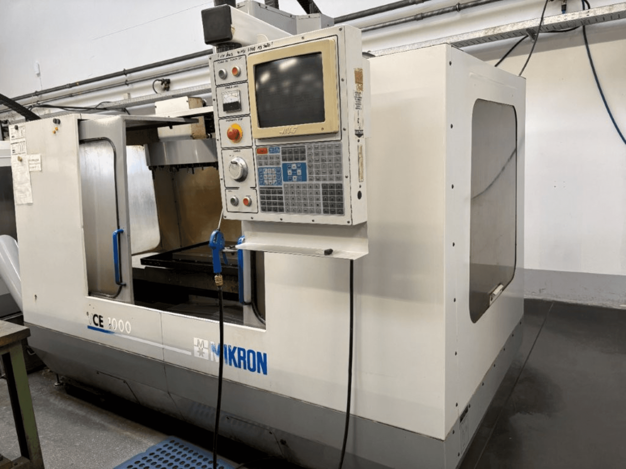 Mikron CE 2000 CNC stroj, pogled sprijeda; ima upravljačku ploču s gumbima i zaslonom, srebrnu vanjštinu i radni prostor.