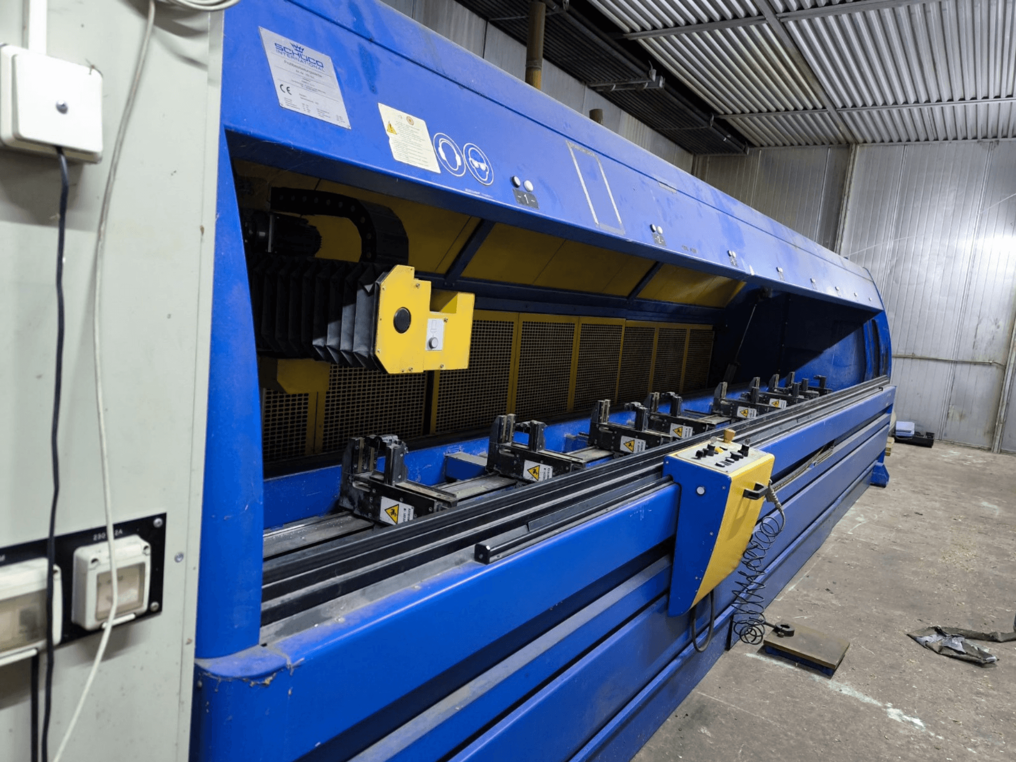 Industrijski stroj za rezanje marke Schneider u plavoj boji, bočni pogled, s vidljivom upravljačkom pločom, remenima i više steznih stanica.