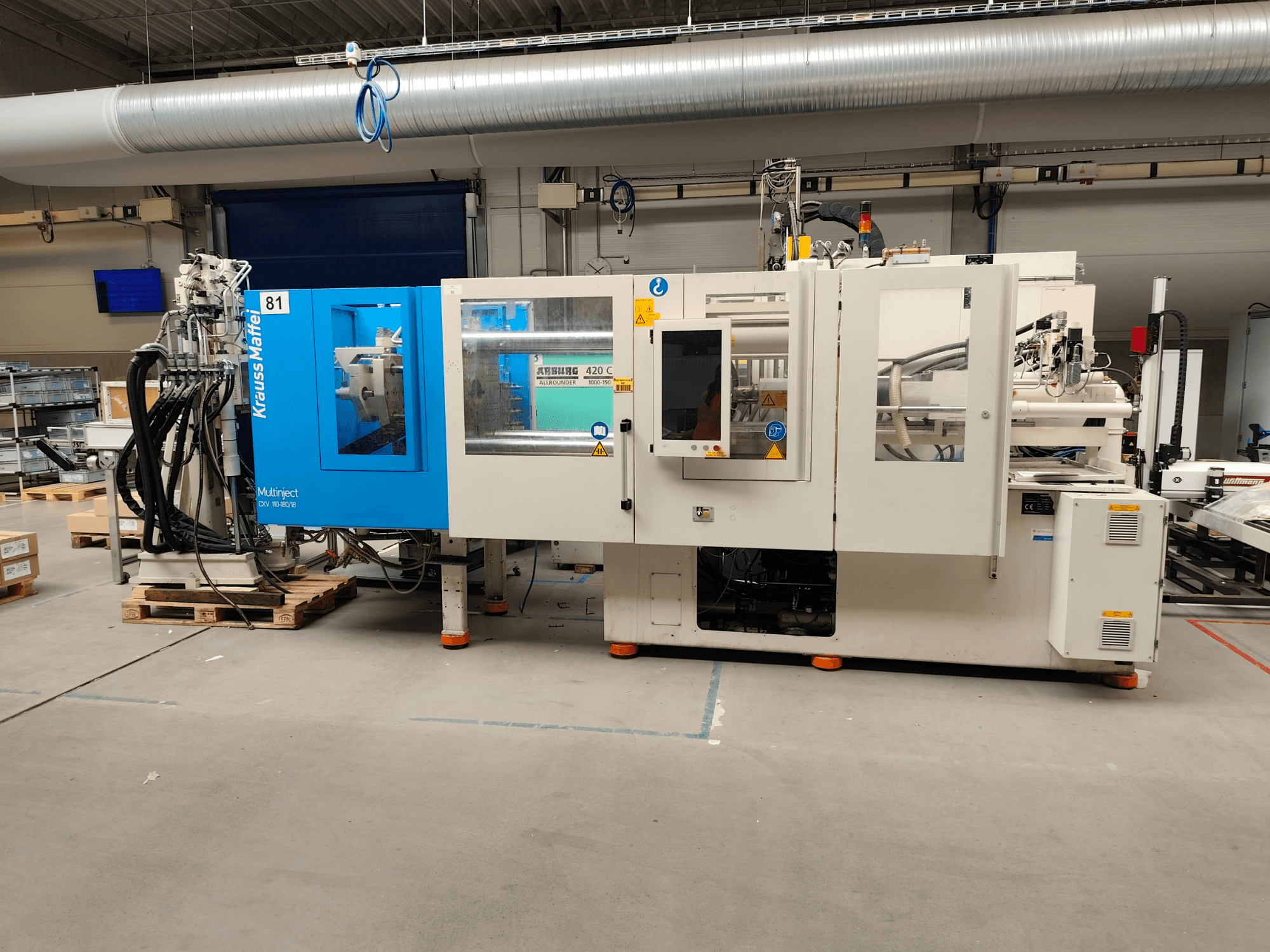Krauss Maffei 110-180-180 CX V hidraulički stroj za brizganje plastike, bočni pogled, prikazuje plavo-bijelo kućište, upravljačku ploču i konektore.