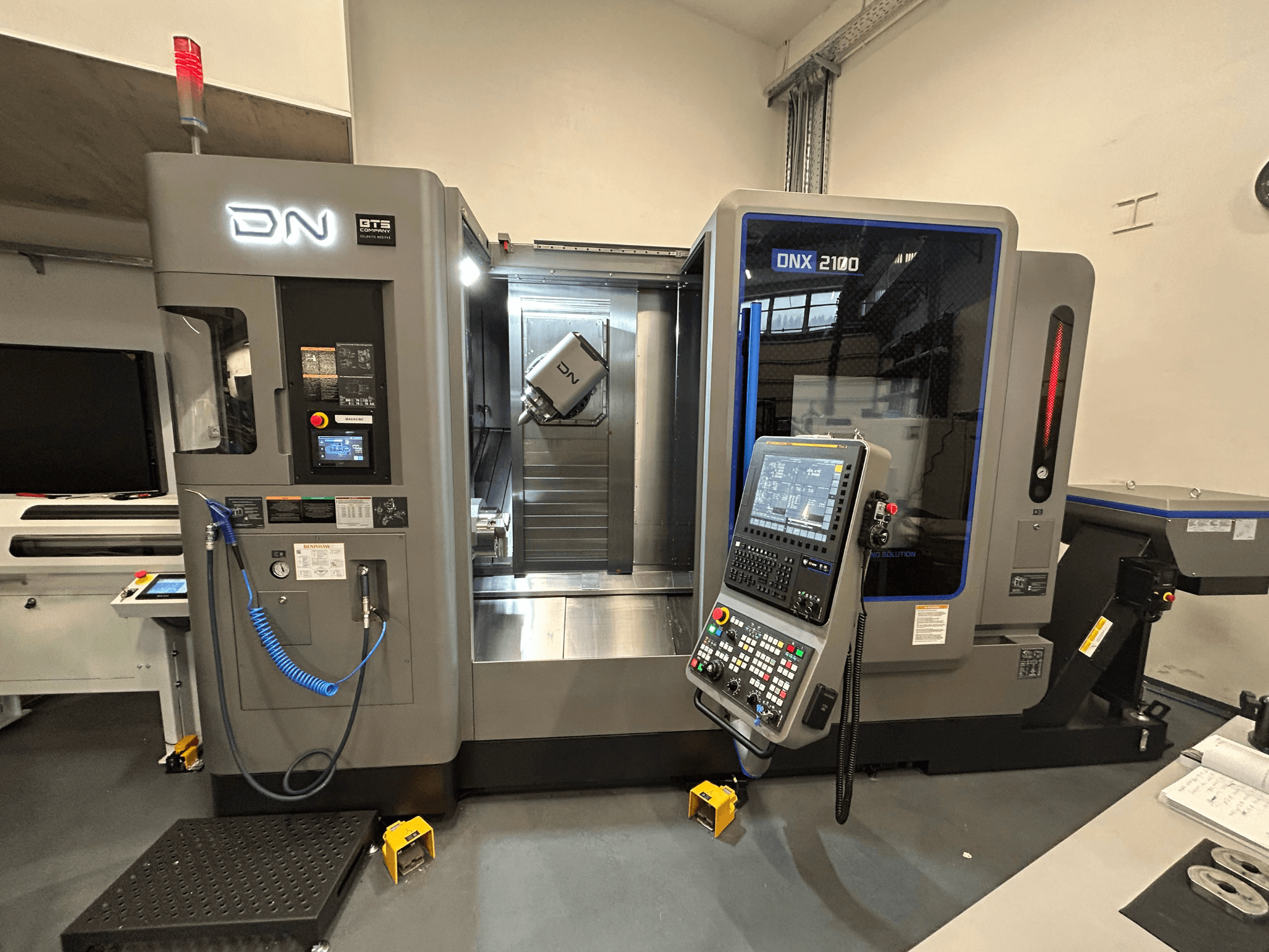 CNC stroj DN ONX 2100, prednji pogled, sadrži upravljačku ploču, radno područje i alat. Opremljen je sigurnosnim svjetlom i indikatorima rada.