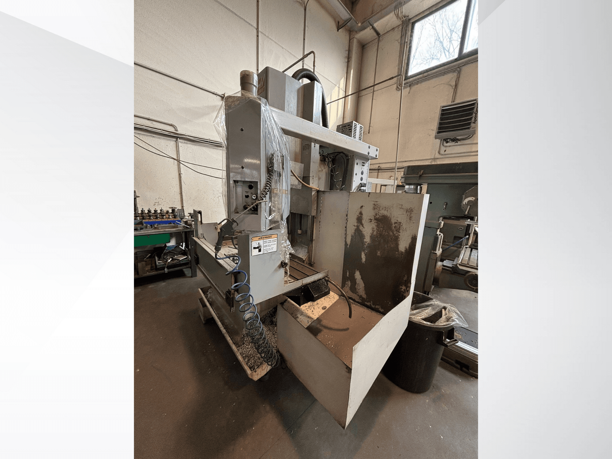 Vertikalna glodalica sa zaštitnim poklopcem, bočni pogled; uključuje crijevo za rashladno sredstvo i vidljivu upravljačku ploču. Idealna za strojnu obradu.