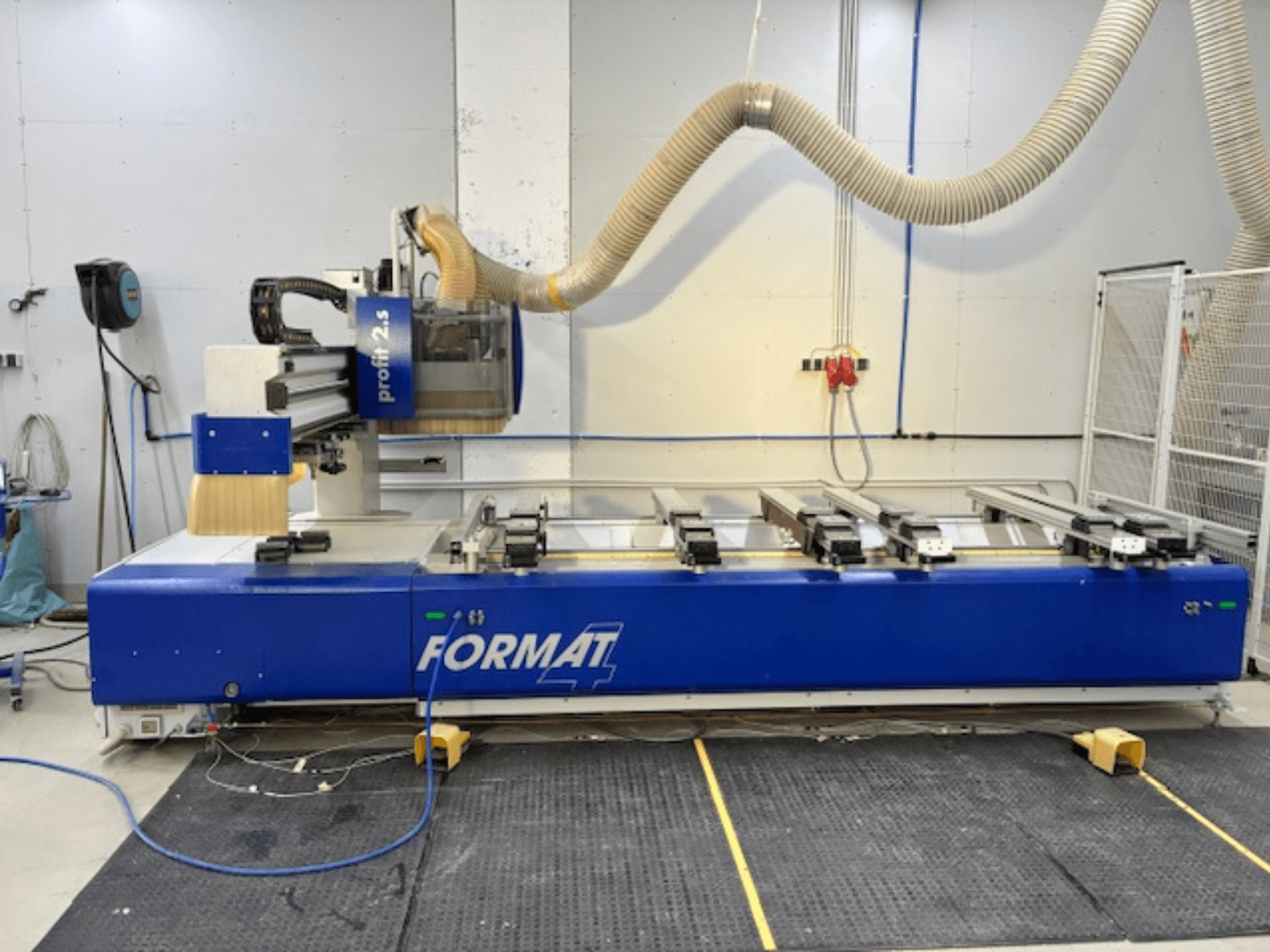 Plavi CNC glodalica FORMAT 4, model Profit 2.5, bočni pogled koji prikazuje područje rezanja i sustav za usisavanje prašine, na gumenoj podlozi.