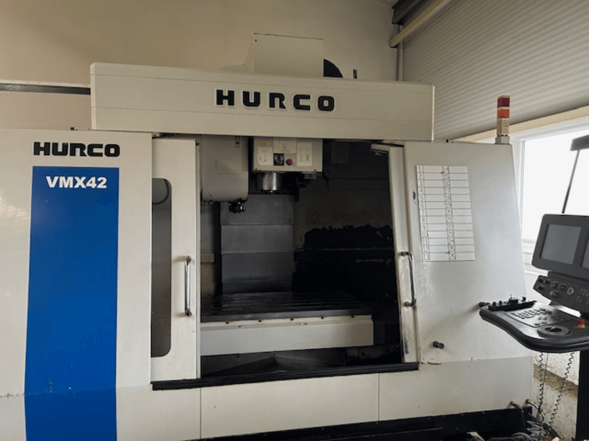 Hurco VMX42 CNC stroj u prednjem pogledu, s prikazom upravljačke ploče, vretena i radnog područja; otkriva se operativni raspored.