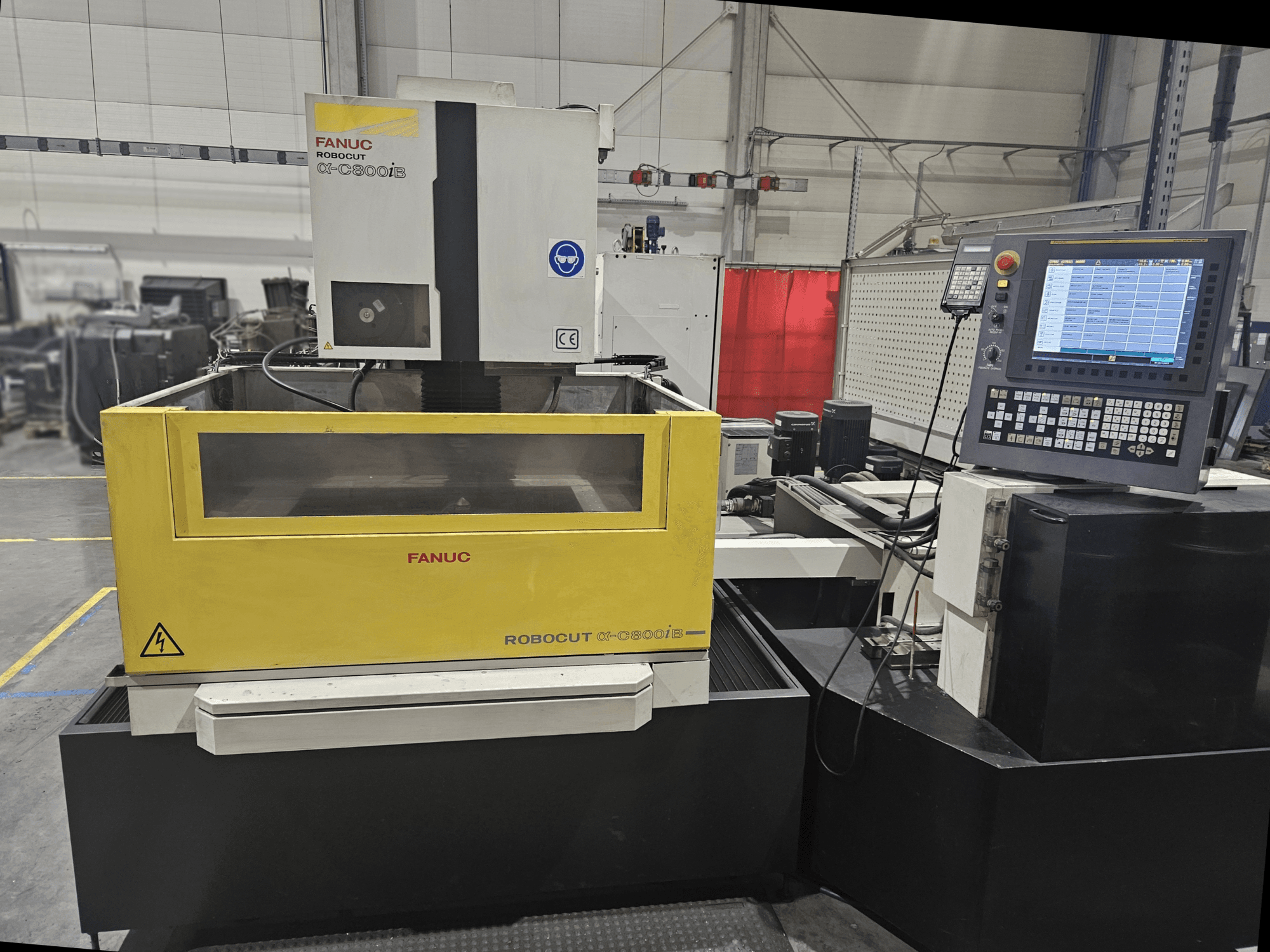 Prednji pogled na FANUC Robocut α-C600iB sa žutim i sivim kućištem stroja, CNC upravljačkom pločom i operativnim zaslonom.