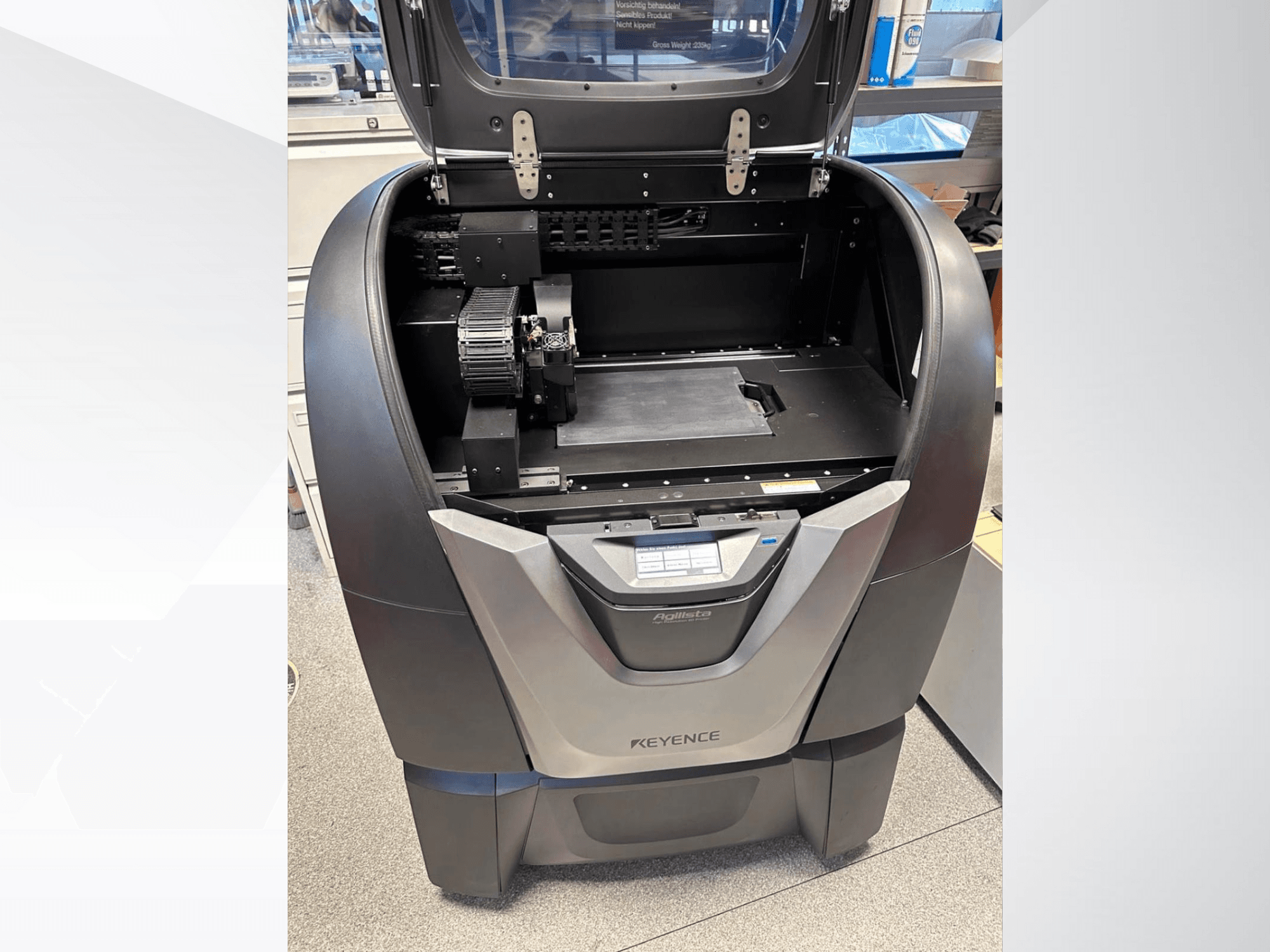 KEYENCE Agilista 3D printer, prednji pogled, otkriva otvoreni vrh, veliku platformu za izradu i unutarnje mehaničke komponente.