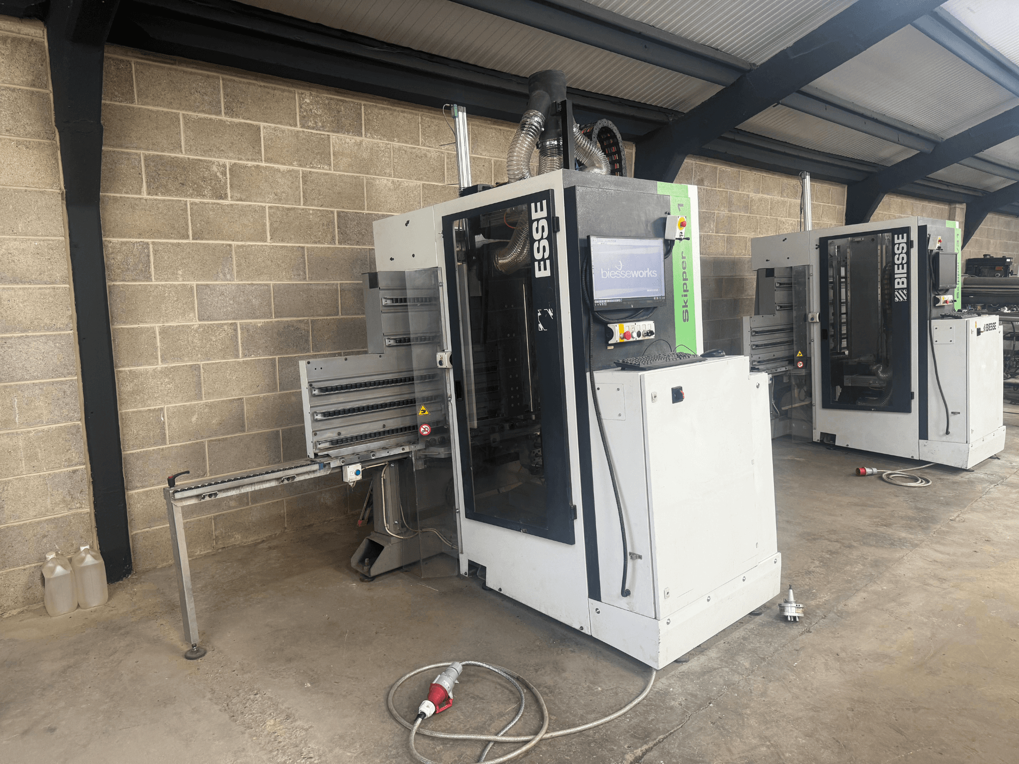 BIESSE Skipper v31 bušilica za drvo u bočnom pogledu, s upravljačkom pločom i susjednim strojevima, smještena u radionici.