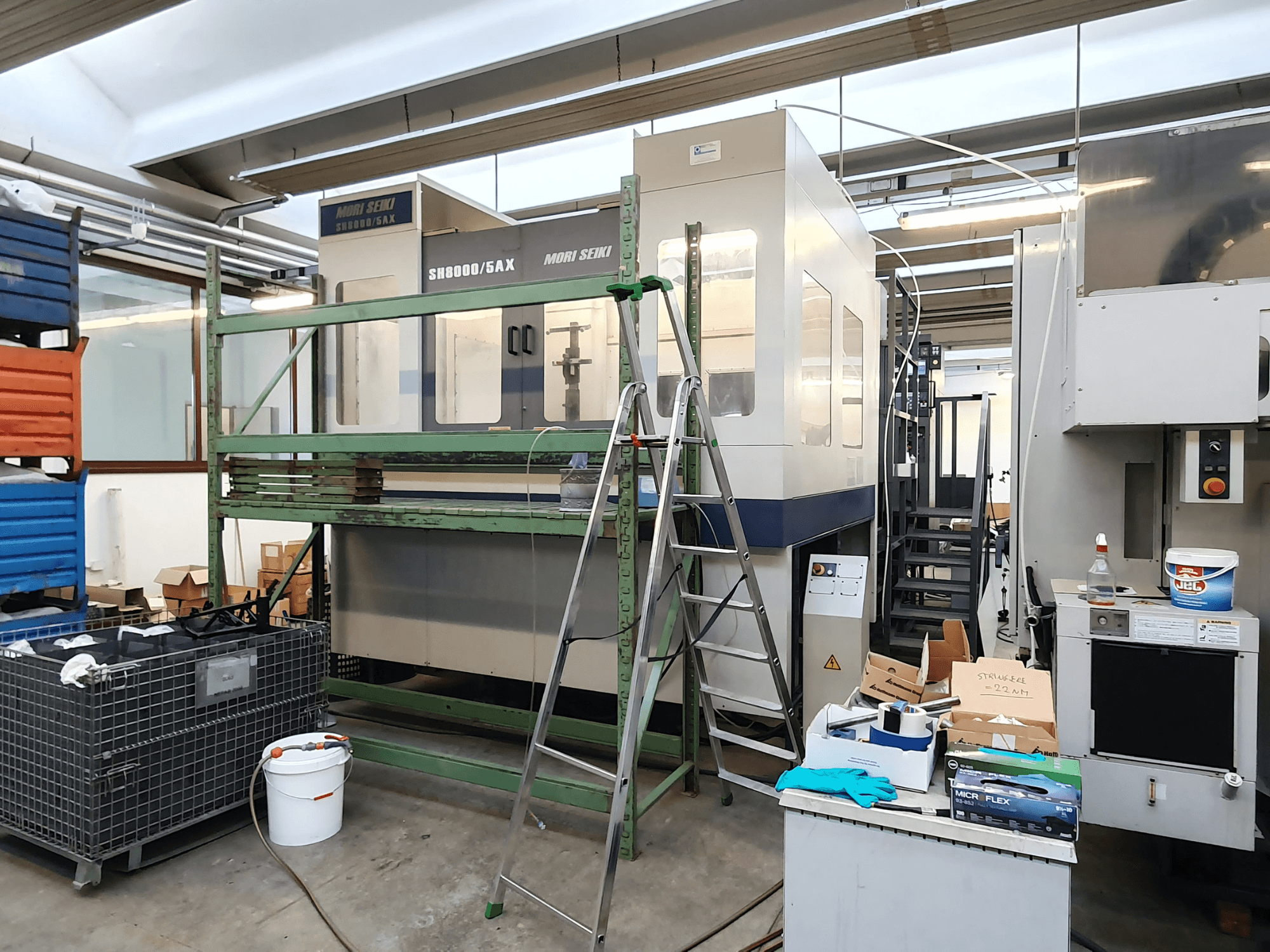 CNC stroj Mori Seiki SH-8000/5AX u radionici, pogled sprijeda, s alatima za radionicu i kutijama za pohranu u blizini.