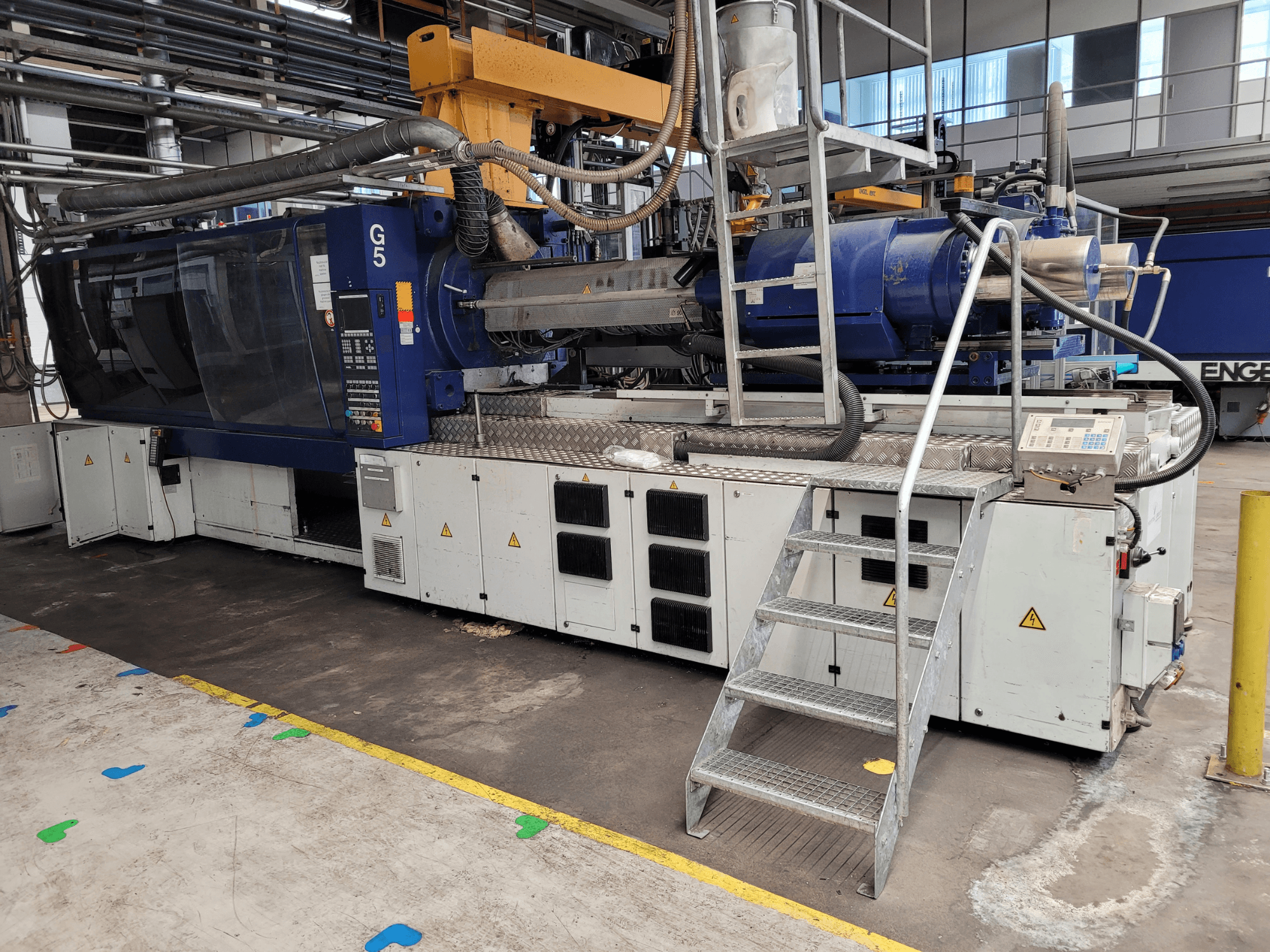 Stroj za brizganje plastike G5, bočni pogled, s vidljivom upravljačkom pločom, ljestvama i radnom površinom od nehrđajućeg čelika.