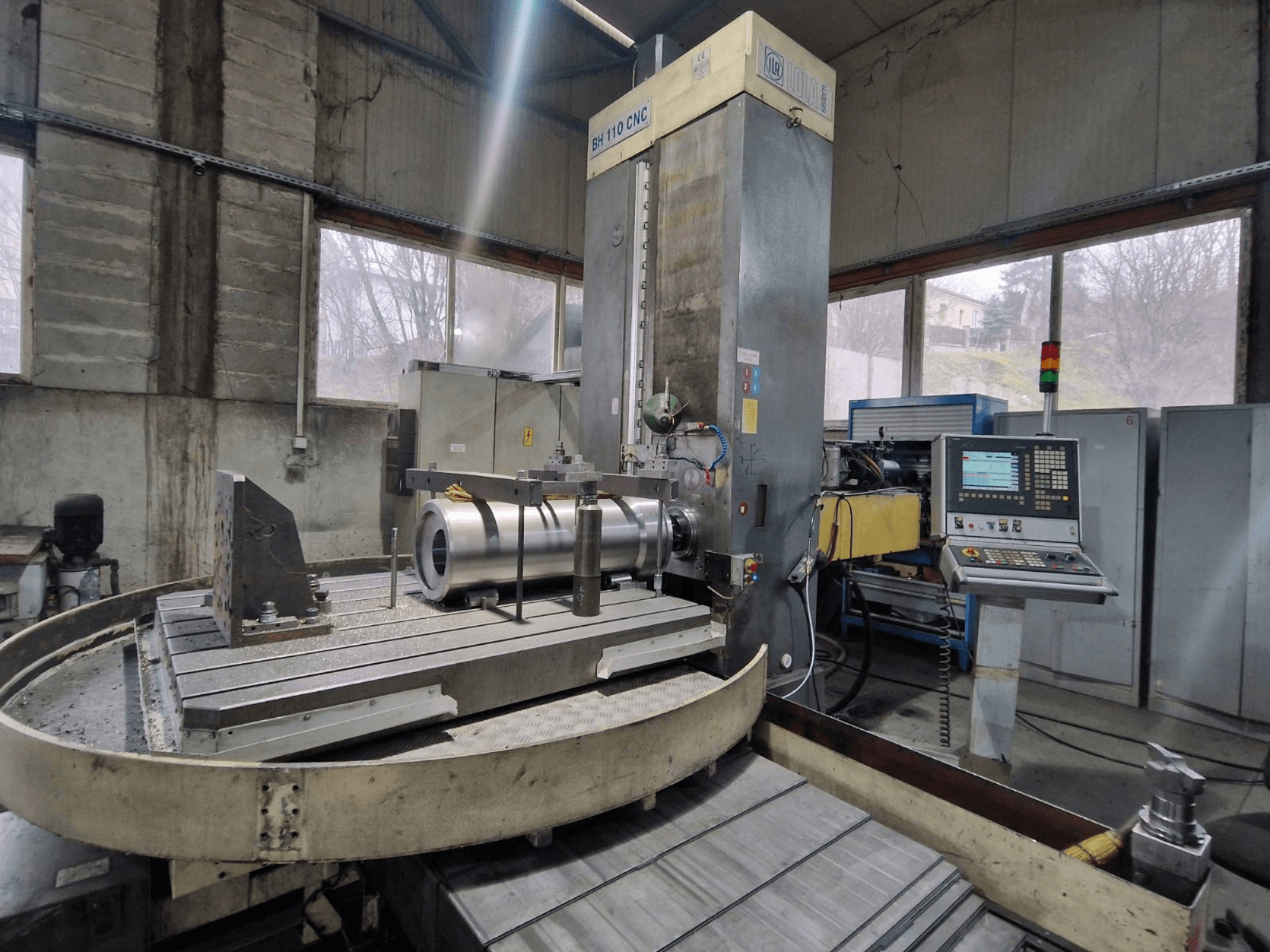 LOLA BH 110 CNC bušilica u radionici, prednji pogled, s metalnim obratkom i upravljačkom pločom.