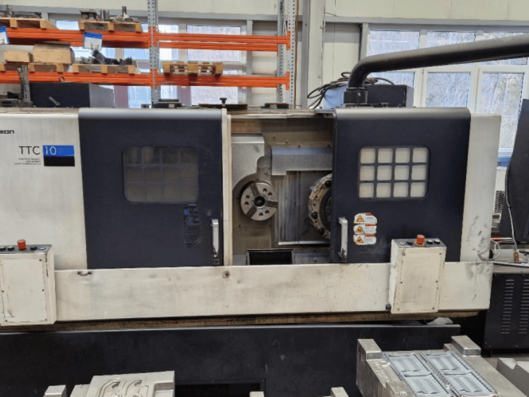 Prednji pogled na tokarilicu TTC 10, s upravljačkom pločom, vidljivim steznim glavama i radnim prostorom s metalnim dijelovima.
