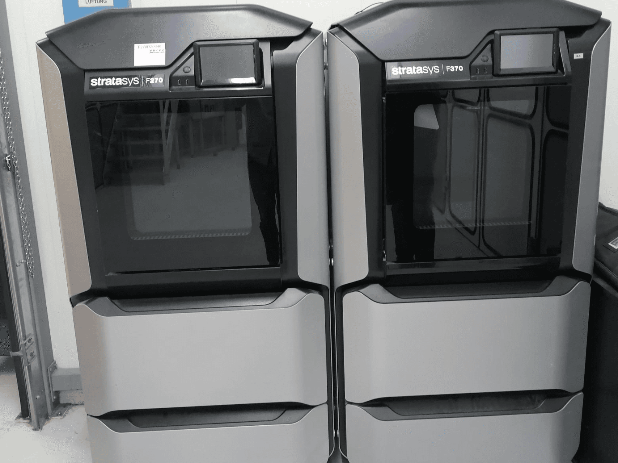 Stratasys F370 dvostruki plastični 3D printeri prikazani u prednjem pogledu, s elegantnim crno-srebrnim dizajnom i kontrolnim zaslonima.
