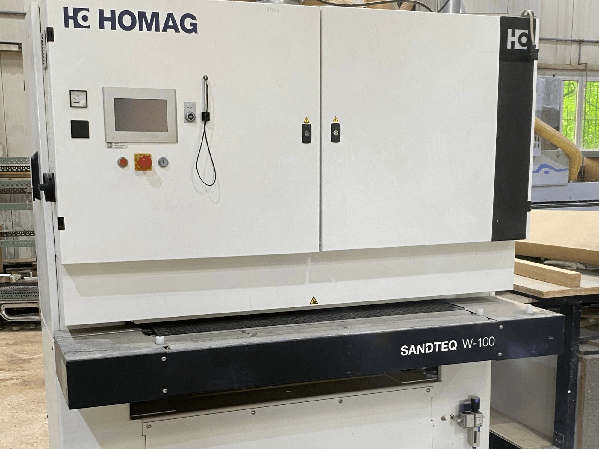 Tračna brusilica HOMAG SANDTEQ W-100 u radionici, s prikazom upravljačke ploče, otvora za prašinu i područja brusne trake. Pogled sprijeda.