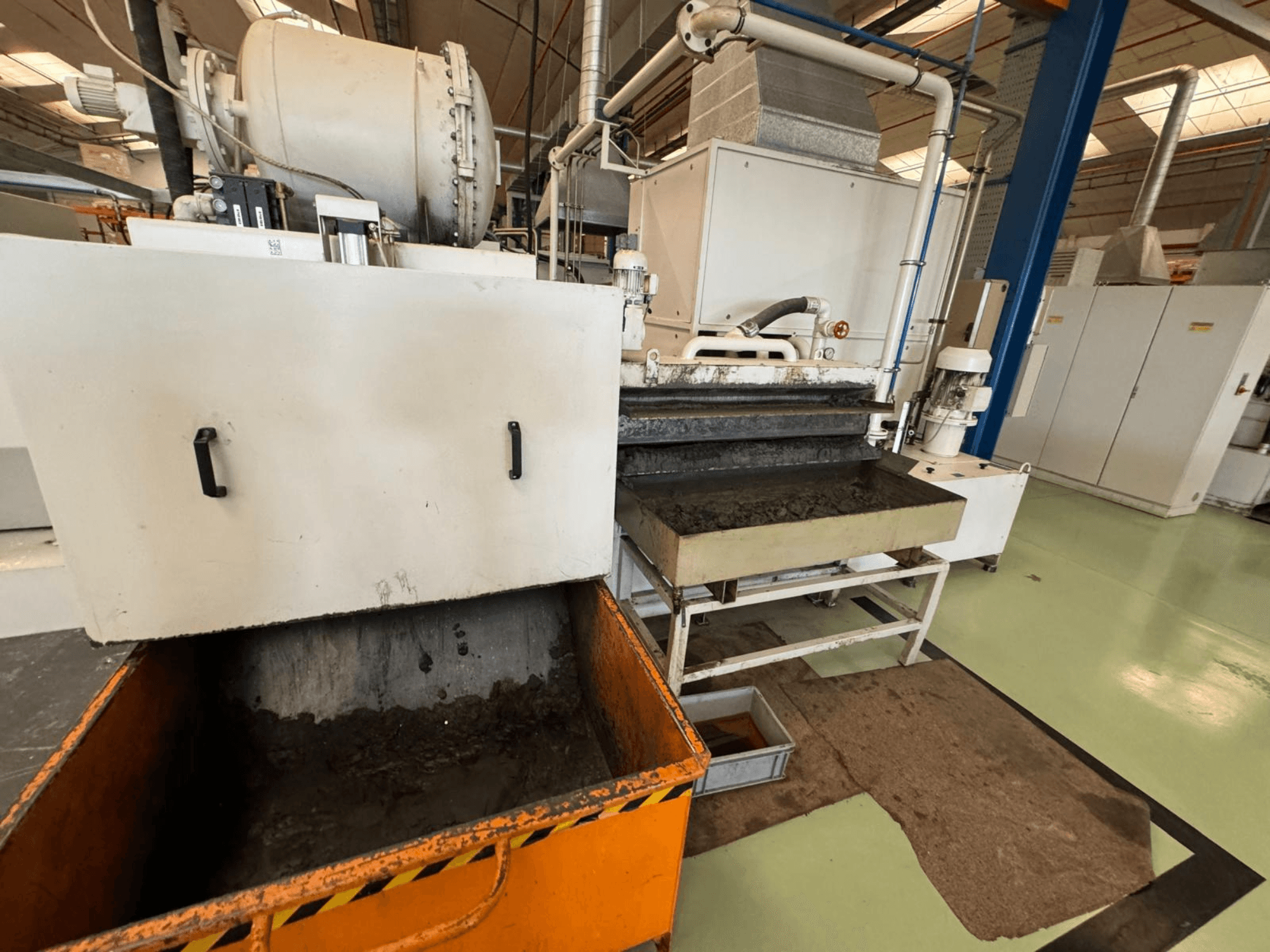 Industrijska oprema za preradu s narančastom kantom za otpad, prednji pogled; sadrži motor, transportere i prostor za održavanje.