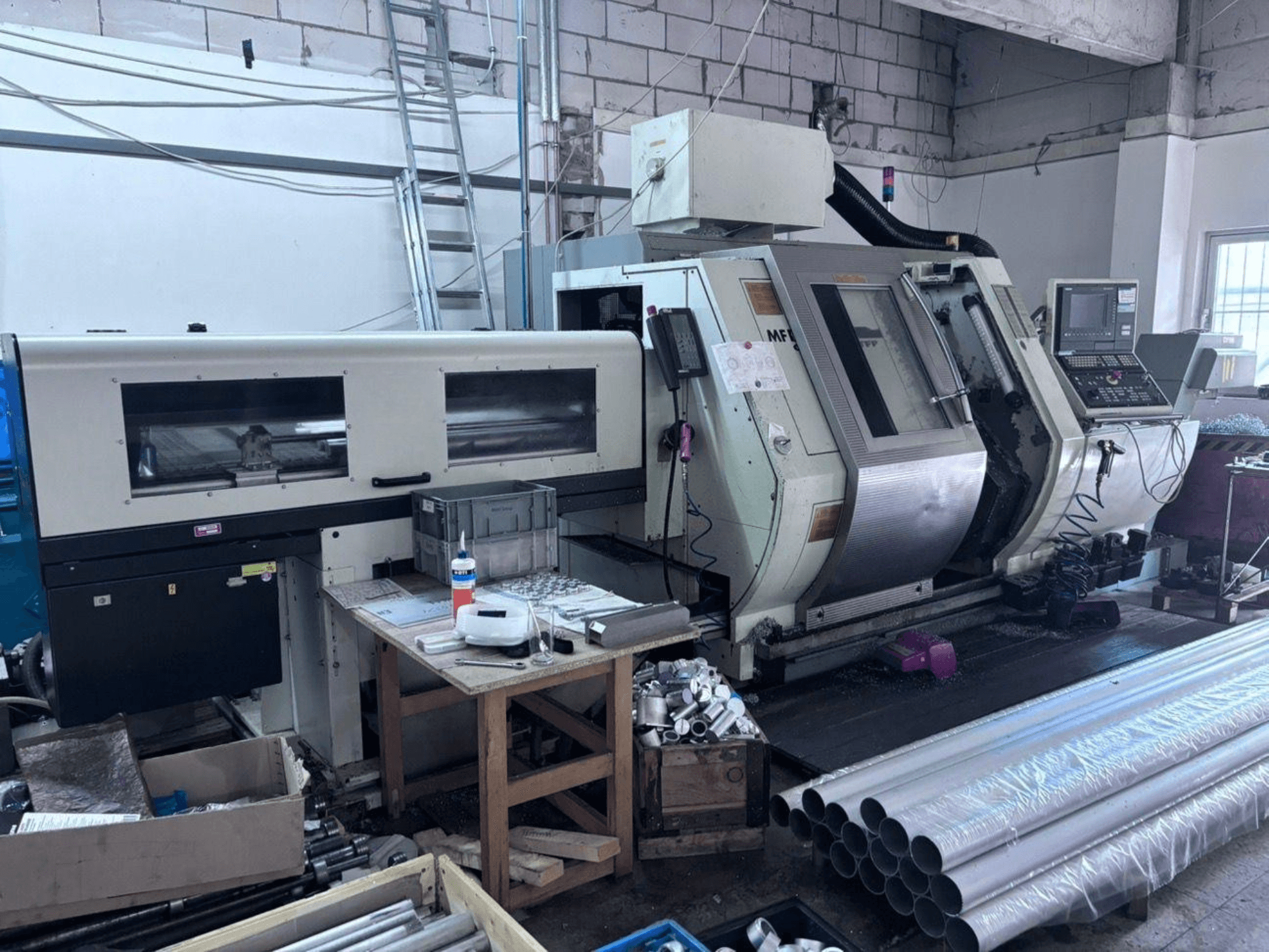 Gildemeister MF Twin 65 Tokarsko-glodački centar, bočni pogled koji prikazuje upravljačku ploču, područje obrade i aluminijske cijevi.