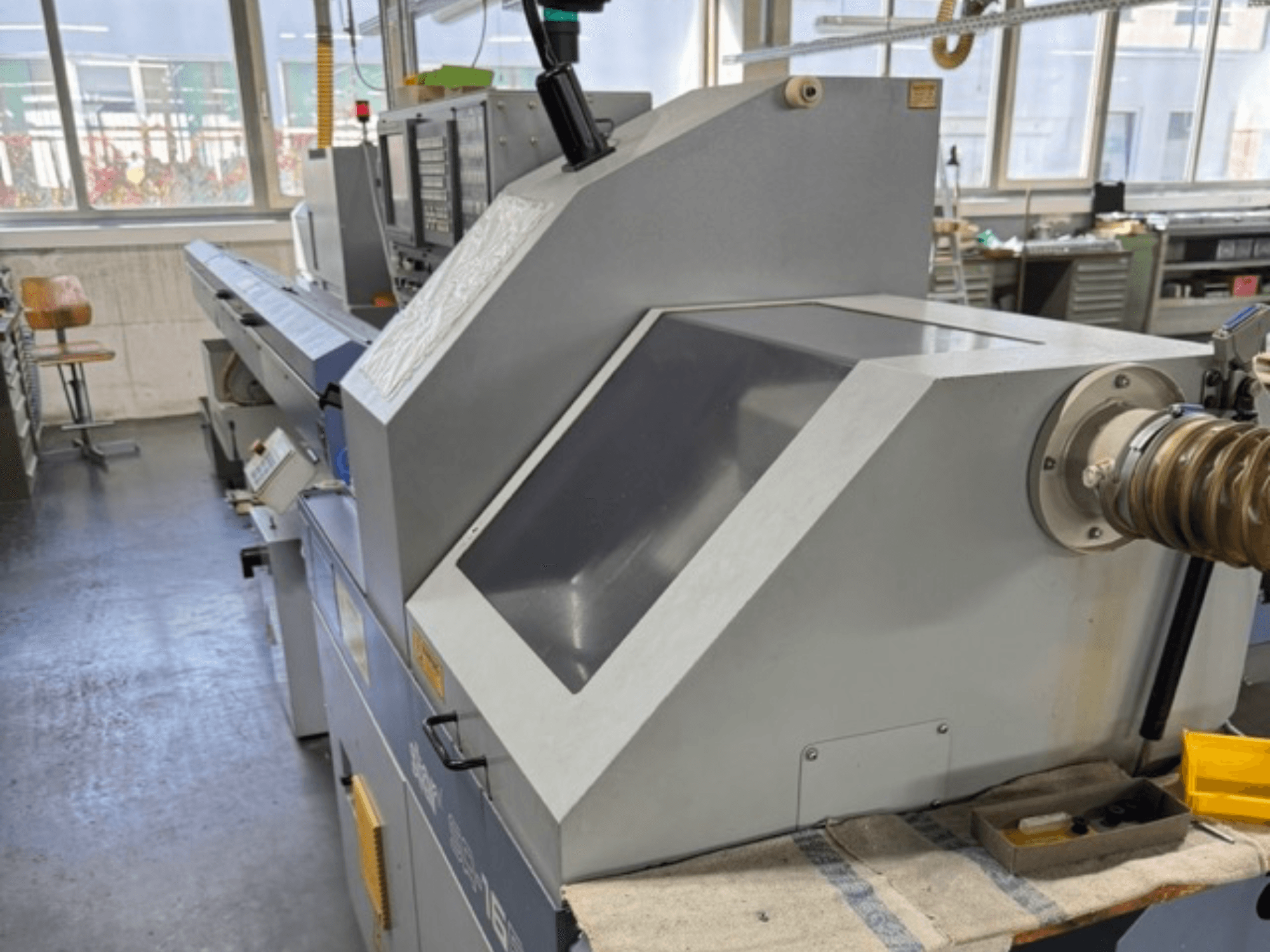 Sivi industrijski stroj gledan sa strane ima veliku kutnu ploču, kontrolne tipke i priključak za crijevo.