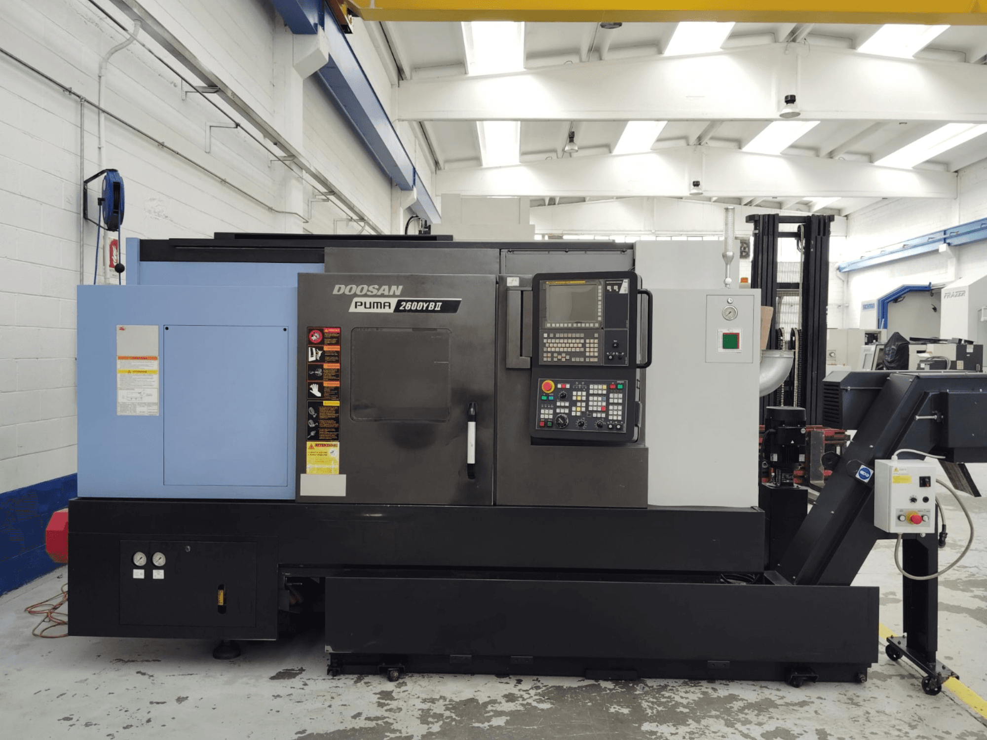 Prednji pogled na horizontalni tokarski stroj DOOSAN Puma 2600YB II s vidljivom upravljačkom pločom i sigurnosnim naljepnicama.