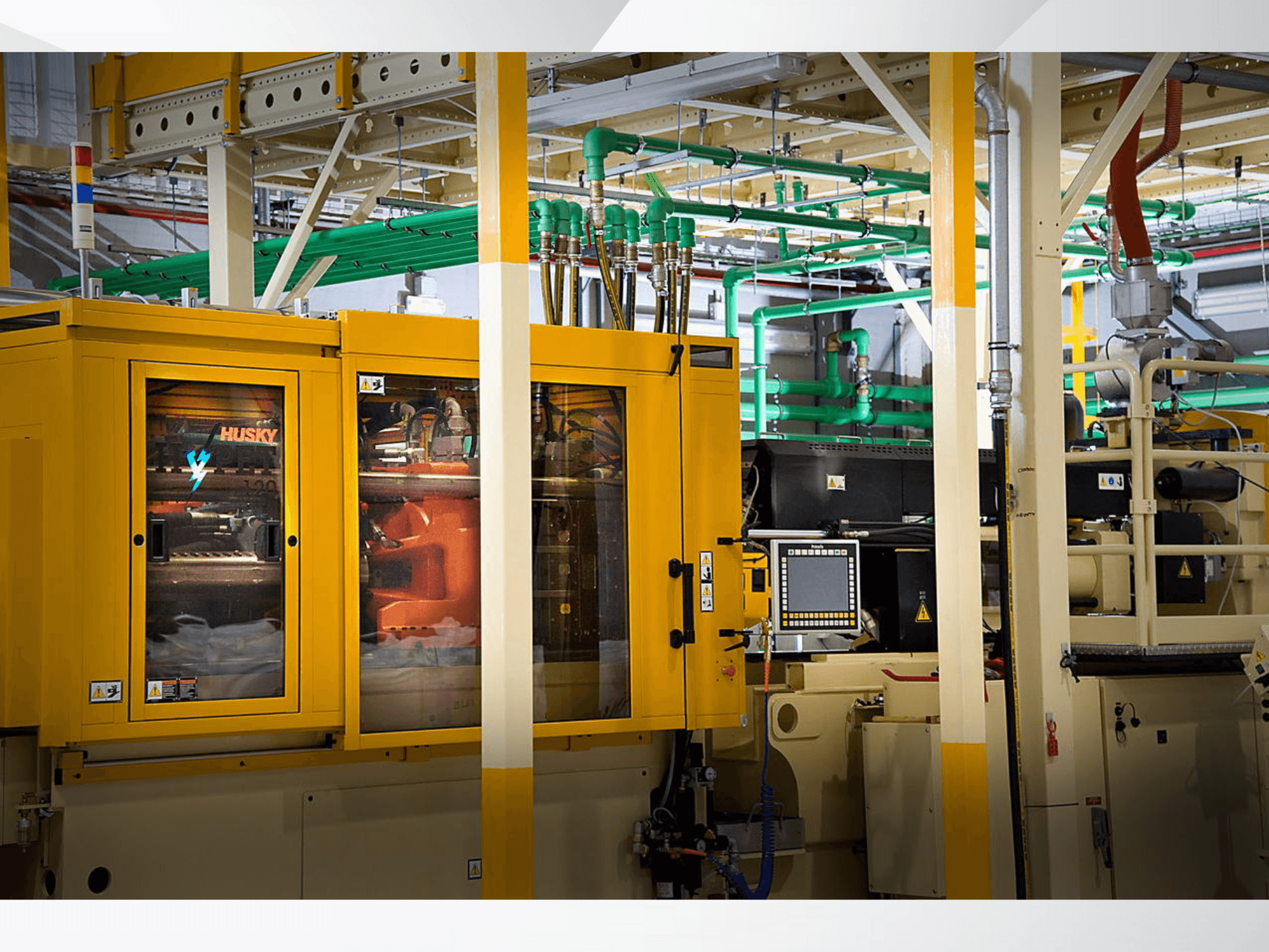 Huskasti industrijski stroj u žutoj boji, prednji pogled koji prikazuje upravljačku ploču i unutarnje mehanizme na pozadini tvornice.