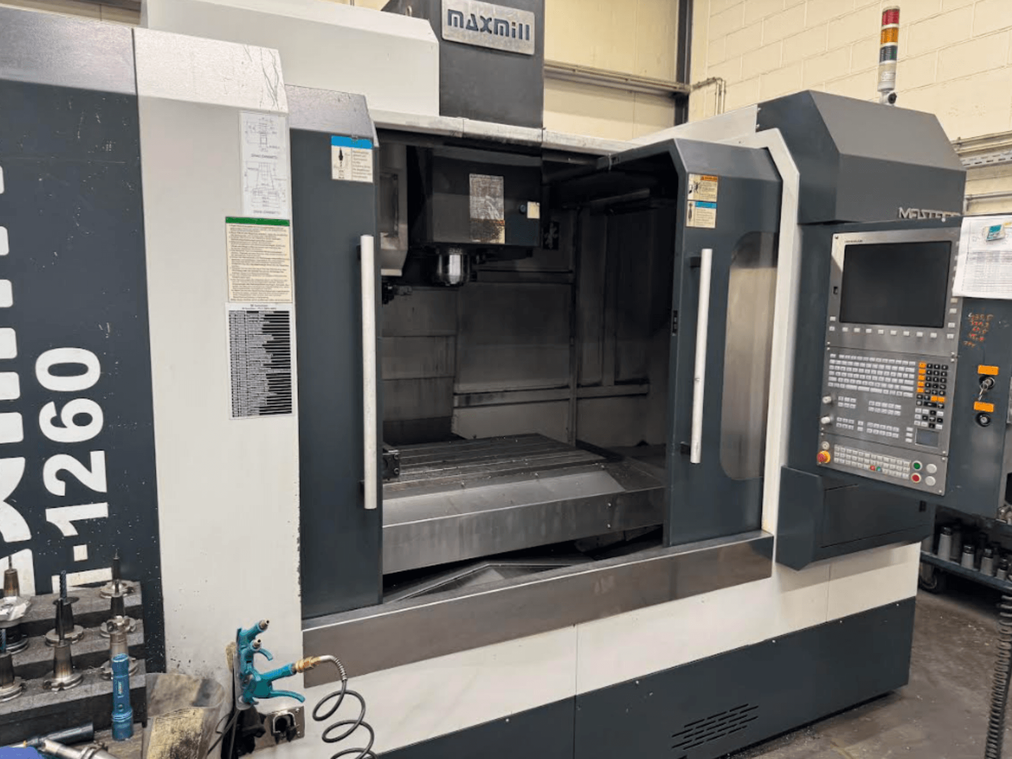 Maxmill CNC glodalica, model M-1260, prednji pogled koji prikazuje prazan radni prostor s upravljačkom pločom i uputama za uporabu.