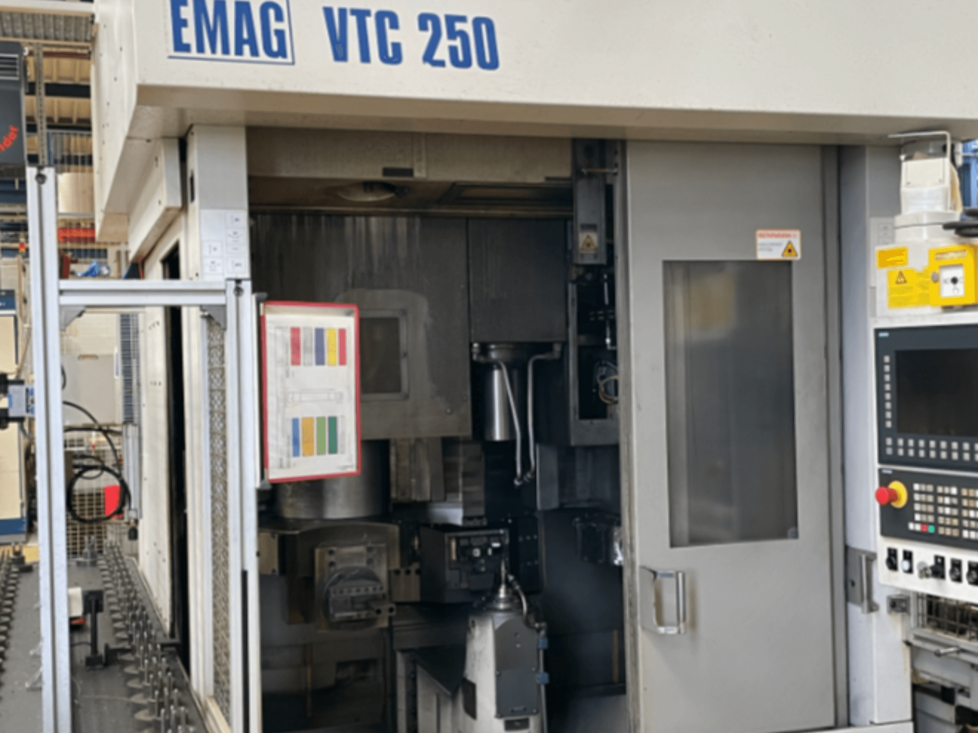 Prednji pogled na vertikalni tokarski stroj EMAG VTC 250, s prikazom upravljačke ploče, operativnog sučelja i otvorenih pristupnih vrata.