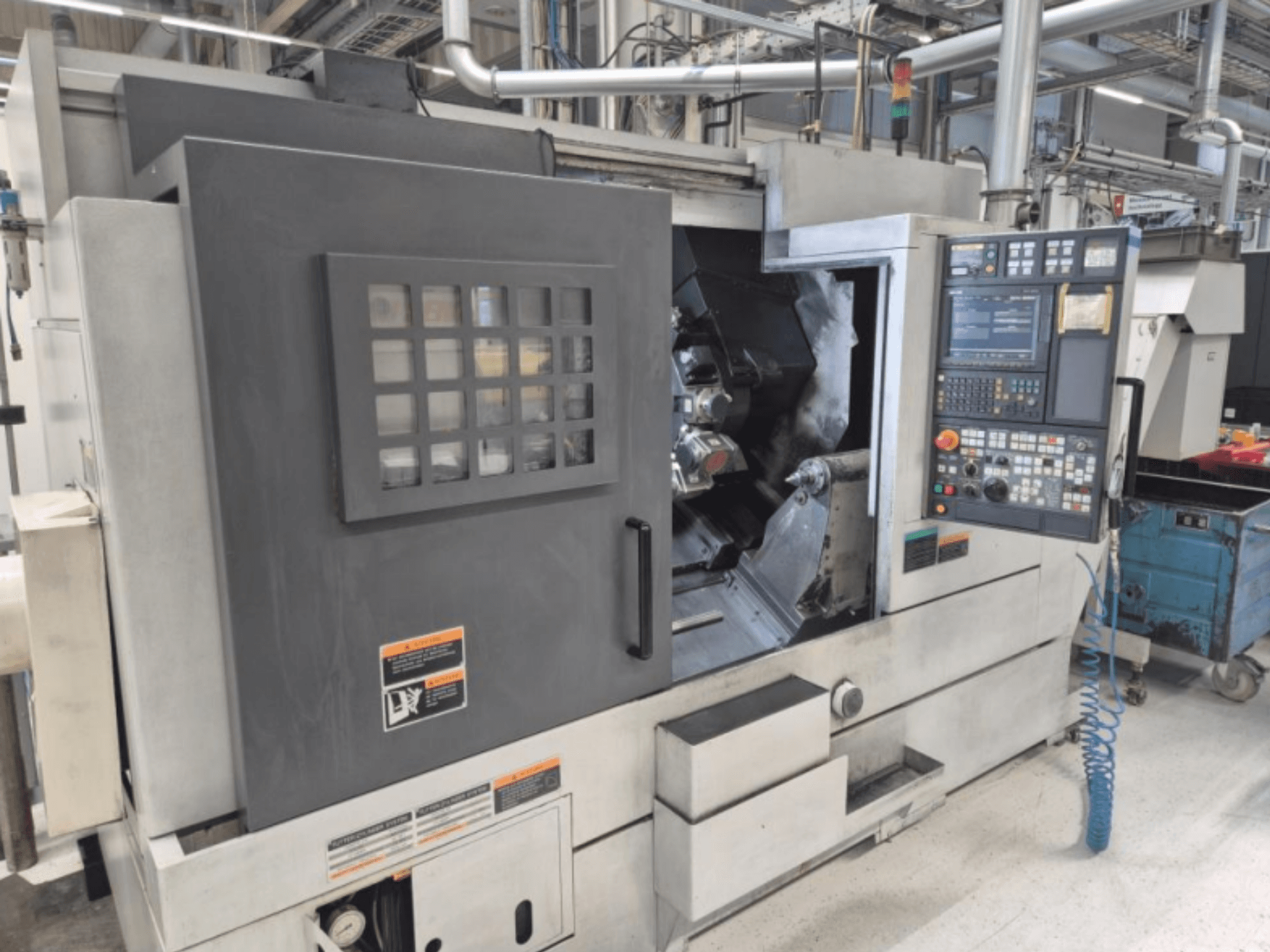 CNC tokarski stroj s upravljačkom pločom, prednji pogled. Ima vidljivo radno područje i sigurnosni prozor, nepoznata marka.