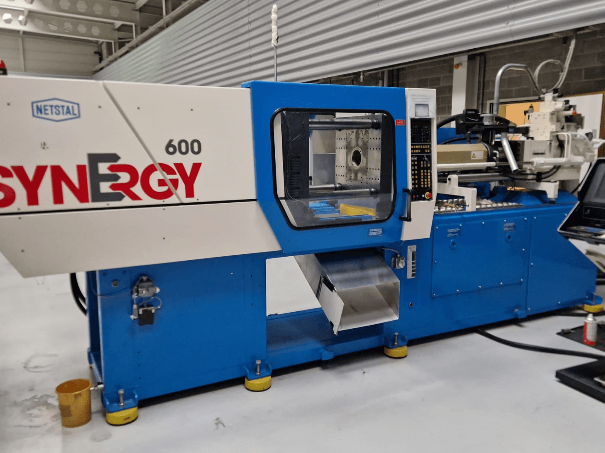 Hidraulički stroj za brizganje plastike Netstal Synergy 600-230, bočni pogled s upravljačkom pločom i područjem za brizganje.