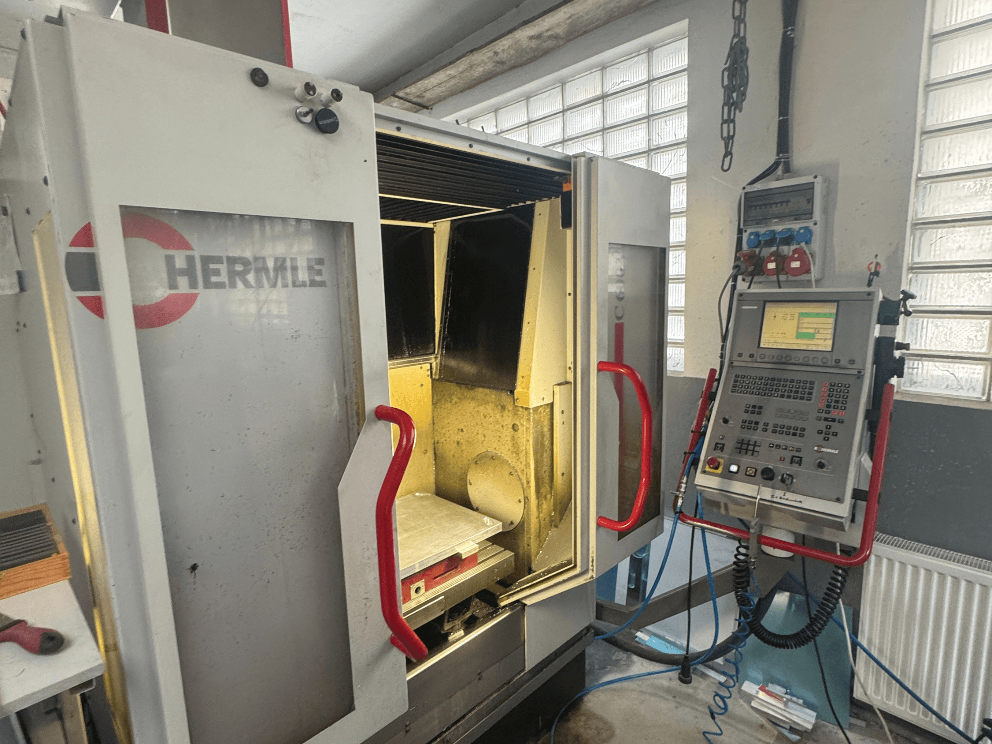 Vertikalni obradni centar HERMLE C600V, prednji pogled s otvorenim vratima, upravljačkom pločom i unutarnjim radnim prostorom.