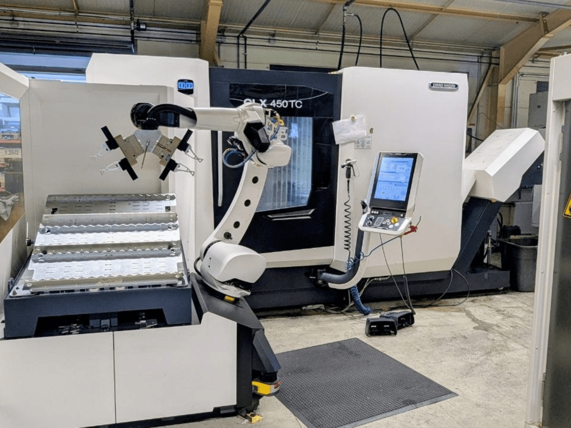 DMG MORI CLX 450 TC s Robo2go, prednji pogled, s prikazom robotske ruke i upravljačke ploče pored stroja.